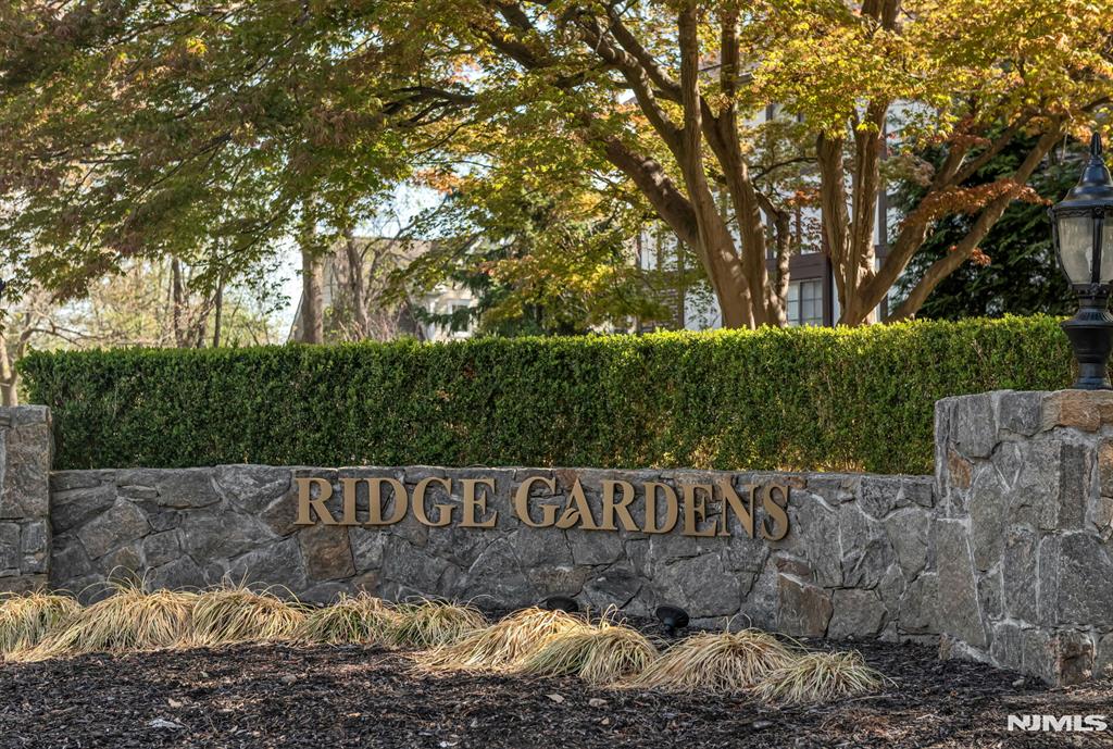 Welcome to this move-in-ready two-bedroom, two-bathroom end unit at Ridge Gardens, where an open floor plan and soaring cathedral ceilings create a bright and airy atmosphere. The main level is designed for both comfort and convenience, featuring a spacious living room with a cozy wood-burning fireplace and sliding glass doors that open to a private terrace. Nearby is a modern kitchen equipped with stainless steel appliances and a dedicated dining area. For ease of living, the primary bedroom suite and laundry are located on the first floor, while the second level offers a private second bedroom, a full bath, and an expansive storage area. Elegant hardwood floors run throughout the entire unit, which is perfectly situated within a community that offers premium amenities including a swimming pool, tennis courts and dedicated parking.