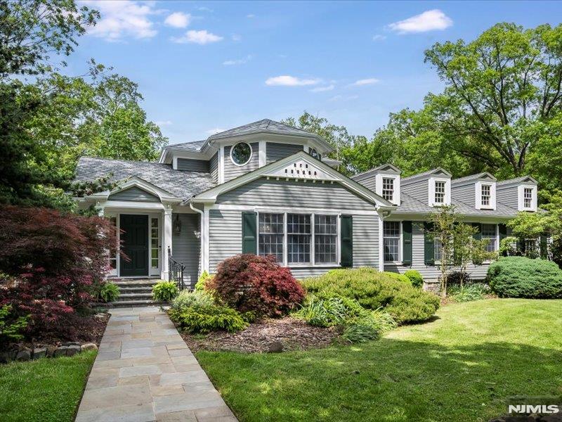 Privacy abounds in this custom Expanded Ranch in desirable North Caldwell! Fully renovated to exacting standards in 2005/2006, the home offers an open floor plan with flexible layout for comfortable living. Main floor highlights include a sleek marble Foyer, formal Dining Room, Chef's Kitchen with walk-in Pantry and center island seating that opens to Living Room with fireplace. Primary Bedroom with tray ceiling, walk-in closet and elegant Bath with radiant heat, a second Bedroom, hall Bath, comfortable Den and rear stairs complete the main floor. Upstairs, a spacious guest Bedroom with furniture-quality built-ins and en-suite Bath with sauna opens to a balcony with peaceful garden views. Ground-level Family Room with fireplace, wet bar and coffered ceiling opens to Patio. Also on this level is a fourth Bedroom, full Bath, home Office, Laundry and access to the oversized 2-car Garage. Lovely covered terrace overlooks exceptional grounds with a stunning dry-stacked fieldstone wall, greenhouse, mature trees and perennial gardens with specimen plantings. A detached Garage/Outbuilding offers many possibilities for an art studio, guest cottage or pool house. Come home to your own suburban oasis!