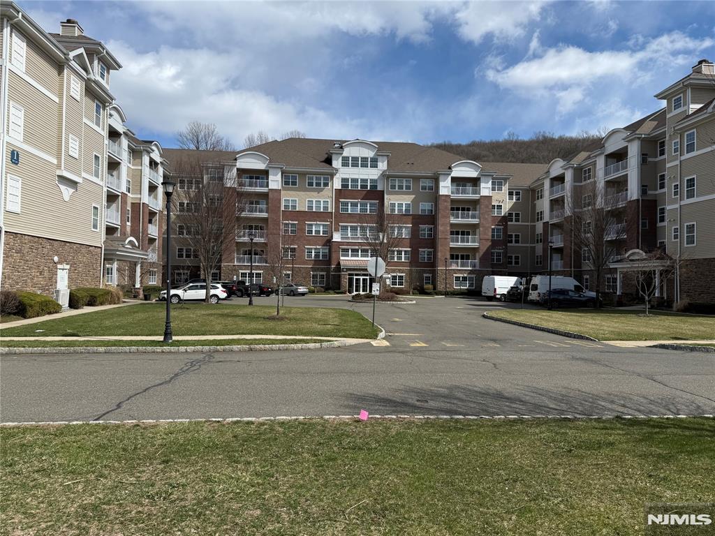 Largest 2 bedroom 2 bathroom model, 2119 SF Westbrook end-unit in Wanaque Reserve, a Del Webb 55+ active adult community, is in the newest building in the complex. This move-in ready home boasts hardwood flooring, a spacious 20x20 primary bedroom ensuite featuring a full bath, tray ceiling and two walk-in-closets. There' a a second bedroom, full bath, eat-in-kitchen with stainless steel appliances, granite countertops, and a tiled backsplash. The living room, dining room and den are highlighted by French doors for added elegance, and the living room's sliding doors lead to a private balcony with seasonal views. Additional features include a larger den, larger laundry room & larger 2nd bedroom, upgrades such as three pot drawers, extra upper cabinets, a laundry area with countertop and cabinetry, wine refrigerator, new hot water heater, and new refrigerator. The home comes with two deeded parking spaces # 61 & 75, a 6x10 deeded storage unit #1F on the same floor, and 24-hour security. Residents enjoy access to a 20,000 SF clubhouse offering a cafe, ballroom, gym, theater, sauna, indoor and outdoor pools, plus more than 45 clubs & activities, including travel club (cruises, trips, casino outings), tennis, pickleball, canasta, poker, golf, and more. Wanaque Reserve provides residents with a luxurious lifestyle focused on modern comforts, security, and community spirit. Recent renovations have created a fresh, updated living environment.