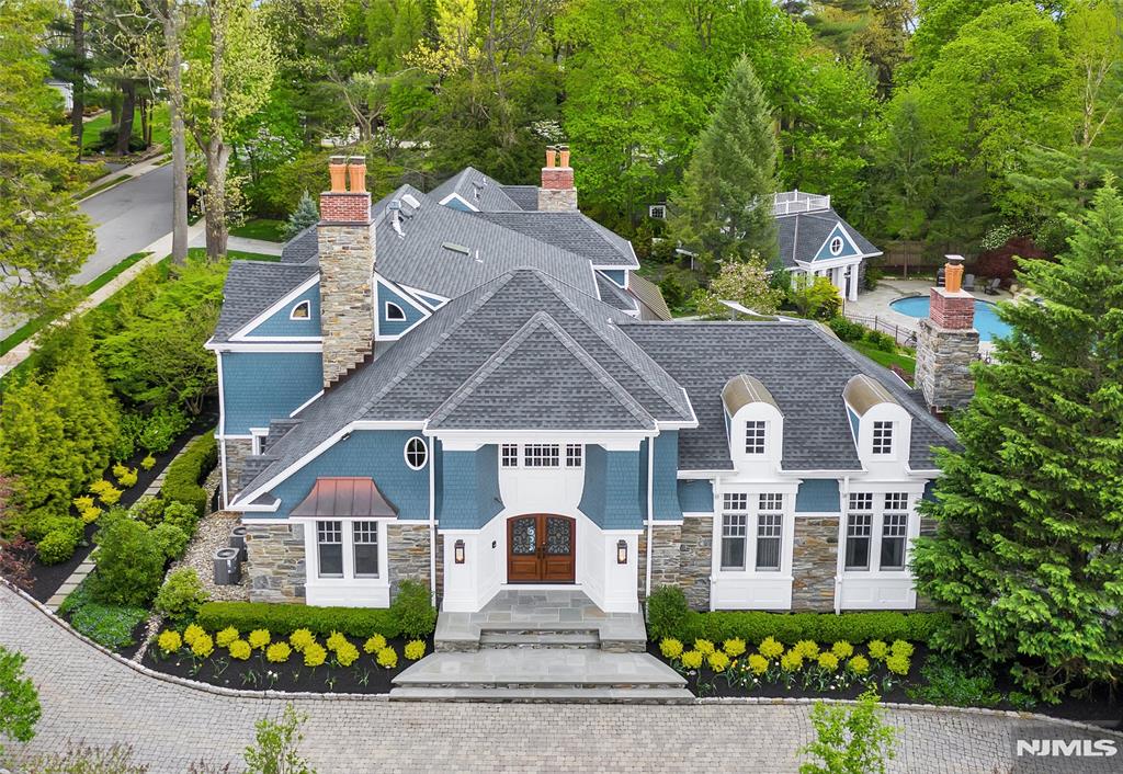 Poised in the prestigious Heights section of Ridgewood, this masterfully designed estate offers over 10,000 SF of sophisticated living space on nearly an acre of resort-like grounds. A true architectural sanctuary, the smart-integrated residence opens with a gorgeous 2-story foyer that leads to a great room at the home's focal point, with soaring ceilings and one of the property's 5 fireplaces. The heart of the home is a culinary dream - a gourmet kitchen anchored by dual 5'x9' Calcutta Gold marble islands and professional-grade Wolf/Sub-Zero appliances, including a built-in Earthstone pizza oven that opens to a family room with a fireplace, both lined with floor-to-ceiling windows and French doors overlooking the private backyard. The versatile floor plan also includes a banquet-sized dining room, stately den, ensuite bedroom/office, mudroom, and access to the 3-car garage. Luxuriate in the primary suite featuring a private balcony, and dual full bathrooms, both with radiant heat and a massive California closet. Entertainment reaches new heights in the expansive basement, boasting a wine room and a state-of-the-art movie theater. Transitioning outdoors, the fenced yard hosts a freeform gunite pool, a massive bluestone patio, and a designer kitchen outfitted with a full suite of Lynx appliances. Completing the home is a fully equipped pool house with a living room, kitchen, laundry, and bedroom/loft - all just a short stroll from downtown, schools, and the train to NYC.