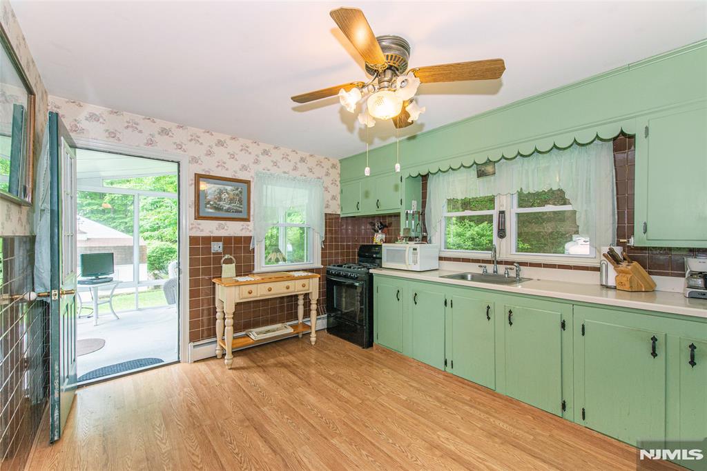 Tucked away on just under an acre and set far from the road, this charming ranch offers a peaceful, wooded setting with convenient access to Route 23 and within an hour of the Lincoln Tunnel. The spacious living room is filled with natural light from a large bay window and centers around a wood-burning stove insert that adds warmth and character. The kitchen retains its vintage charm and flows into a bright, glass-enclosed sunroom lined with sliders, perfect for relaxing or hosting with views of the private, tree-lined yard. Both bedrooms are generously sized, and hardwood floors lie beneath the carpets throughout the main level, ready to be revealed. The full walk-up attic and partially finished basement (with laundry and storage space) offer significant potential for added living area, workshop, or hobby space. A whole house generator provides peace of mind, and the attached one-car garage adds everyday functionality. The property also includes a screened porch, a side yard shed, and mature landscaping. Backed by woods and full of possibilities, this home is ideal for buyers looking for space, privacy, and a chance to make it their own.