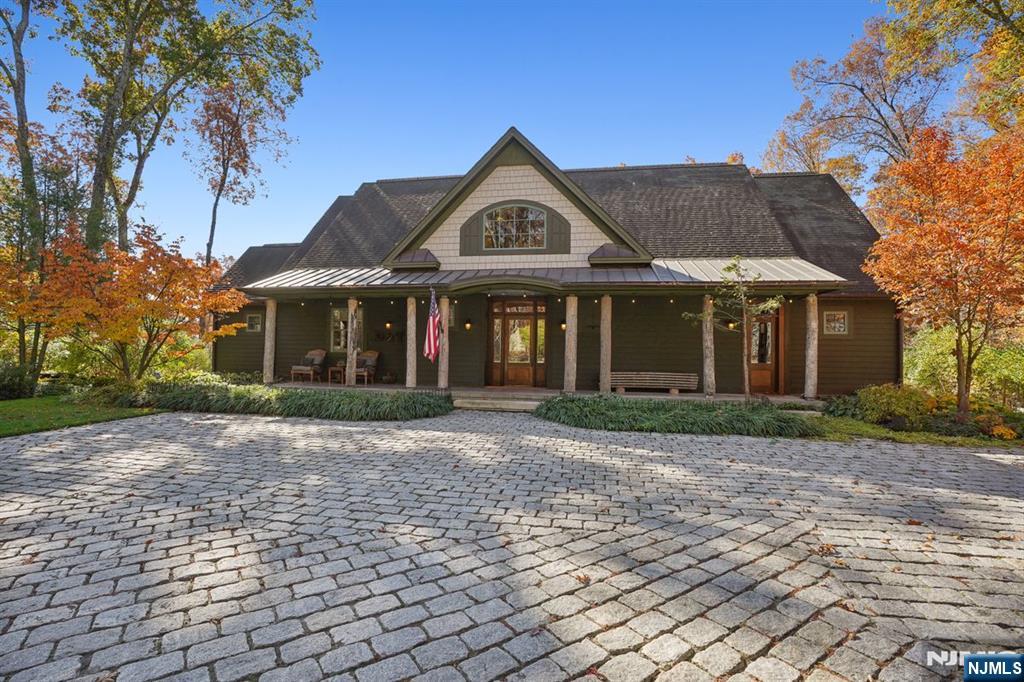 Custom-built 4-bedroom, 3.5-bath home on approximately 13 acres in Allequest Estates, a private enclave in Allamuchy.The property features wooded acreage, private hiking trails, open lawn areas, mature trees, and a farm setting. Covered front and rear porches, stone hardscaping, multiple outdoor gathering spaces, and a covered hot tub provide year-round outdoor living.Offering approximately 2,933 square feet, the home includes a vaulted great room with cathedral wood ceiling, wood stove, loft overlooking the main living area, wide-plank wood flooring, and large windows with wooded views. The kitchen opens to dining and gathering spaces with direct access to outdoor living areas, while multiple French doors create a seamless connection between indoor and outdoor spaces.The primary suite includes a spacious bath with double vanity.Additional bedrooms and flexible living areas accommodate guests, office space, recreation, or hobby use. Additional features include a sauna, exercise room, generator, high-speed internet, walkout lower level, covered porches, and extensive storage.Convenient to I-80 and regional commuting routes, the property is approximately one hour from New York City and near dining, shopping, coffee shops, grocery stores, and services in Hackettstown.Nearby recreation includes Allamuchy Mountain State Park, Jenny Jump State Forest, and Pequest Wildlife Management Area.A well-maintained custom home offering privacy, acreage, outdoor recreation, and accessibility.