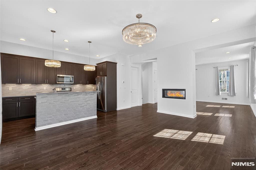 **Call Charmy Morzaria at 609.619.2198 directly to tour this home** Welcome to this sought-after Northeast-facing END-unit townhome in the desirable Wright Place community of Wood-Ridge. Beautiful landscaping and a flower-lined walkway create a welcoming first impression. Featuring front and rear entrances, a 2-car garage, and a 2-car driveway, this home offers space and convenience. The first level includes 9-foot ceilings, abundant natural light, generous storage, and a junior suite with a full bath. The main level features 10-foot ceilings, oversized windows, an open-concept living and dining area, a dual-sided fireplace, private deck access, and a powder room. The updated kitchen offers stainless steel appliances, modern cabinetry, beautiful countertops, a pantry, and breakfast bar. The third floor includes a primary suite, two additional bedrooms, full hall bath, and laundry. Hardwood floors and two-zone HVAC throughout. Close to parks, dining, NJ Transit, NYC transportation, and community amenities including playground, dog park, tennis, and pickleball courts.