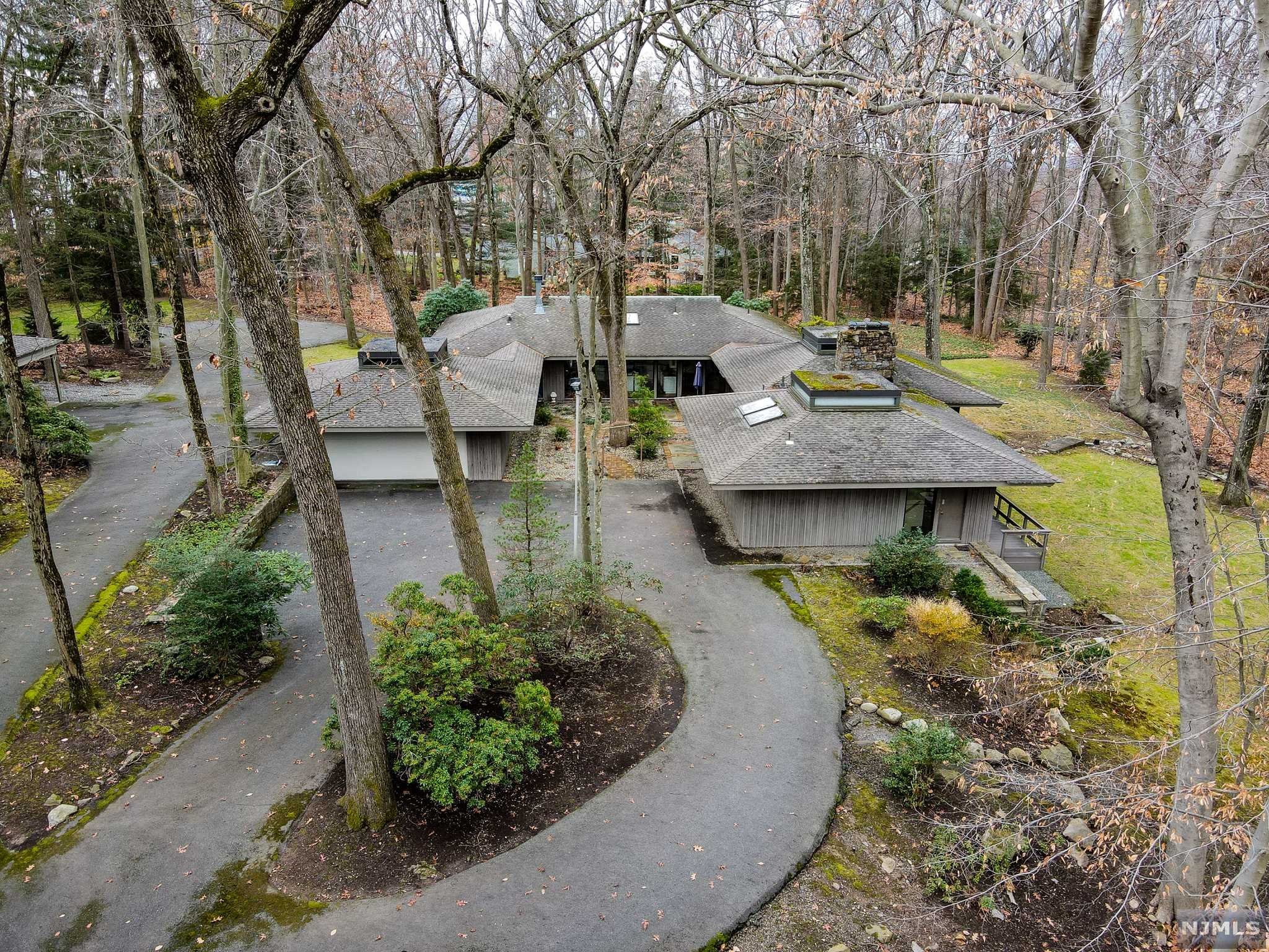 Welcome to "One Duck Pond Road"! Custom built Frank Lloyd Wright-inspired home, sitting on a highly desirable tree covered 3.579 acre lot in the old Beechwood Farms area of Alpine. Main living spaces feature original redwood ceilings and floor to ceiling windows throughout. The home includes a recently updated kitchen with fireplace and skylight, large dining room and living room with beautiful wooded views, doors to a wrap around deck, and a running stream nearby. Master suite has its own sitting area with an ample master bath in addition to 4 other bedrooms. Lower level living area has 2 large family/game rooms, a home office, wet bar, laundry, storage and a sauna with shower. 3 zone heat and forced hot air, 2.5 septic fields, 2 sump pumps, 3 hot water heaters, 2 car garage and 2 car carport. Update the existing home or build new on this spectacular property!