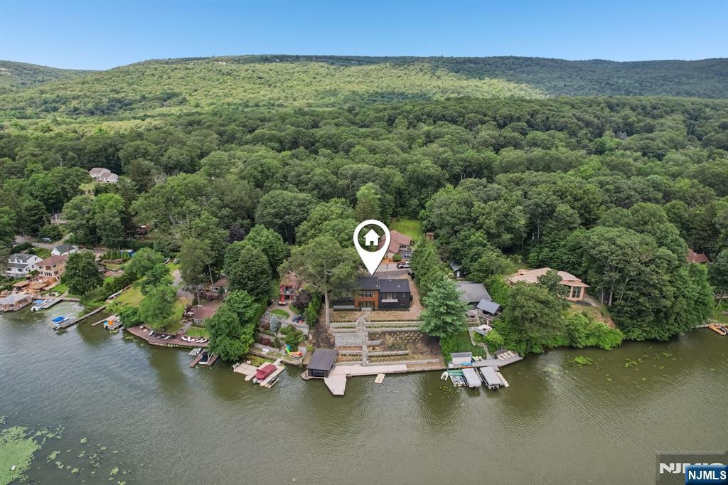 Welcome to an exceptional luxury retreat in sought-after West Milford. This stunning 5-bedroom, 4.5-bath custom home offers the perfect blend of refined elegance, superior craftsmanship, and breathtaking lake views.From the moment you arrive, you'll be captivated by the home's impressive presence and meticulous attention to detail. Inside, a thoughtfully designed open-concept layout showcases soaring ceilings, rich architectural finishes, and an abundance of natural light. The gourmet chef's kitchen is a true showpiece, featuring high-end appliances, custom cabinetry, and an oversized island perfect for both everyday living and entertaining on a grand scale.The expansive living and dining areas flow seamlessly, highlighted by designer touches and panoramic views that bring the outdoors in. A luxurious primary suite offers a private sanctuary, complete with a spa-inspired bath and serene lake vistas. Each additional bedroom is generously sized, with beautifully appointed bathrooms that provide comfort and privacy for family and guests alike.Step outside to experience resort-style living, where stunning outdoor spaces are designed to maximize the picturesque surroundings. Whether hosting gatherings or enjoying quiet mornings overlooking the water, this home delivers an unparalleled lifestyle.Perfectly positioned in a prime location, this one-of-a-kind property combines tranquility, luxury, and convenience making it a rare opportunity you won't want to miss.