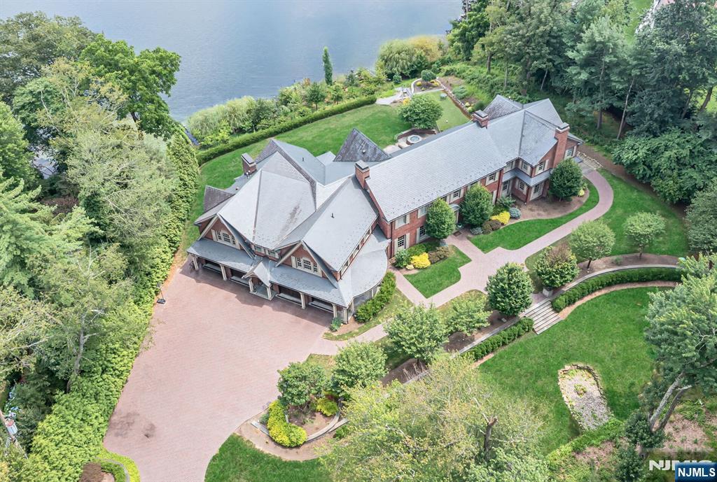 Where Dreams Touch the Water! Welcome to an extraordinary lakefront estate where timeless beauty meets tranquil living undoubtedly one of Franklin Lakes' most captivating treasures. Set on 2.7 magical acres along the shimmering shores of Franklin Lake, this enchanting all-brick Manor was thoughtfully designed as a creation of elegance & warmth. From the moment you arrive, peace & quiet grandeur surrounds you. The slate roof, curved lines, & graceful architecture speak to a home built not just with materials, but with intention. Inside, a story unfolds across 13 rooms of refined comfort & charm. Curl up with a book in the richly paneled great room/library, gather by the fire in the sunlit grand living room, or savor mornings in the breakfast room, wrapped in light with breathtaking lake views. The heart of the home an artisan kitchen with twin islands & handcrafted details opens to a 24x31 family room with a wall of windows. Upstairs, the primary suite is flooded with light, framed by nature, & enhanced with his & her dressing room/closets & exquisite marble bath & steam shower. A walk-out lower level is pure joy offering spaces to play & gather from the game/media rooms to a Pub room with wet bar. A heated driveway welcomes you home in every season, while the grounds invite morning coffees overlooking the lake & unforgettable sunset dinners under the stars. This is more than a home- it is a once-in-a-lifetime chance to have land, light, & luxury a true sanctuary on the lake!