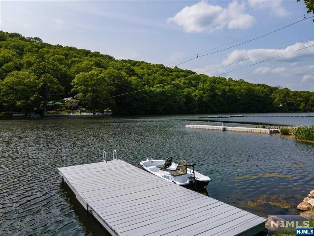 This lakeside gem, nestled in the Hamburg mountains of Hardyston Township, offers year-round enjoyment. Whether it is warm weather, swimming, fishing, and boating, or cold weather ice skating, ice fishing, or skiing, this house offers a multitude of activities to enjoy. Turnkey home with major furniture pieces included. Beds and bureaus, living, dining, kitchen, full gym, outdoor dining, grill, lounge and umbrellas. TESLA solar system (top of the line Tesla system) for own electric use and variable back-up allocation. Replaces need for a generator. 50 Amp electric car charger. Toys such as three paddleboards, one small boat with electric motor are also included. This lakefront oasis has a level yard to the water, a private dock. Great storage hidden away. Full office with enough space for two. Views from the living level are of the mountain across the lake. The Association also offers two association beaches with playground, grassy area, covered picnic area, sandy beach (lifeguard