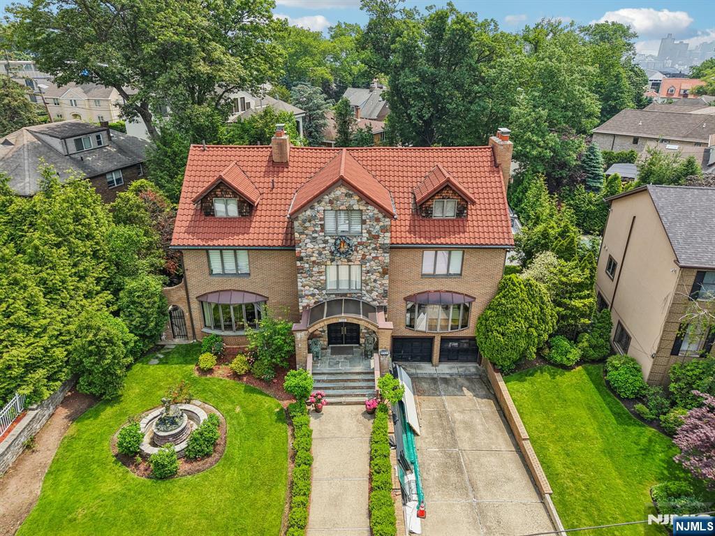 Nestled in the exclusive Bluff section of Fort Lee, this 5 BRs, 4.1 BAs residence offers approx. 4k sq ft of luxurious living space across 4 floors. Designed for discerning buyers, this home seamlessly blends quality craftsmanship w/ timeless elegance. As you enter the home, explore the grand gathering room w/ wall to wall glass windows, stone fireplace, a parlor w/ coffered ceilings and chandelier. Dine in the formal dining room which opens to the eat-in kitchen w/ SS appliances, granite countertop, a wet bar / bev station, wine fridge, walk-in pantry, and powder room. The solarium w/ floor to ceiling windows, multiple skylights brings radiant natural sunlight throughout the day and tranquil evenings at night, and multiple patio doors lead to the wooden deck which opens up to a resort like oasis. Newly installed heated, in-ground pool w/ a hot tub, and outdoor spkrs. The manicured lawn w/ sprinklers and grilling area perfect for outdoor entertaining. Upper floors feat the living quarters. A primary suite w/ vaulted ceiling, private enclosed terrace, wood fireplace, en suite full bath, dual vanities, jacuzzi, shower, and sauna. Hallway sitting area, add'l 2 BRs and 1 BA. Upper level feat a spacious guest BR w/ closet, office, and full BA adorned w/ marble tiles. The finished lower level w/ a DEN, laundry room, office / storage, access to attached 2 car GAR, and half bath complete the home. An incredible value with unlimited potential and possibilities!