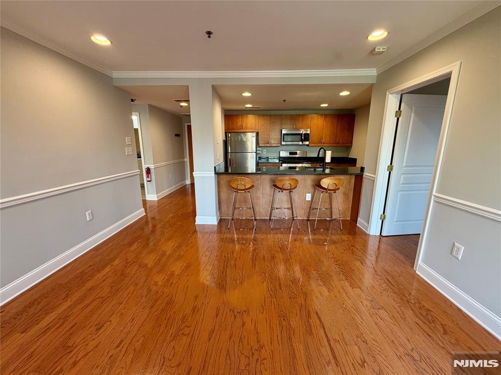 Love Hoboken? Experience comfort and convenience with this well cared for 2 bedroom, 1 bath condo with a modern open kitchen to the living area freshly painted and with moulding/trim. New sliding doors and a large window opens to a long balcony which faces the interior ( not street facing ) affording a quiet space and privacy. Large windows in the primary bedroom enable plenty of natural light and treetop views. The second bedroom features double closets - plenty of storage. The bathroom has a whirlpool tub, new cabinet, sink and faucet plus a beautiful storage mirror. Stainless steel appliances, granite counters, wood faced cabinets, Hardwood floors and newer LG W/D in unit - add to the contemporary feel. The modern brick and steel building also features an elevator, gym for residents and Butterfly MX intercom system. In unit parking may be available for a separate fee. Freshly painted, custom closets, central AC - this home is move in ready. Close proximity to the path, train, bus, parks and schools.