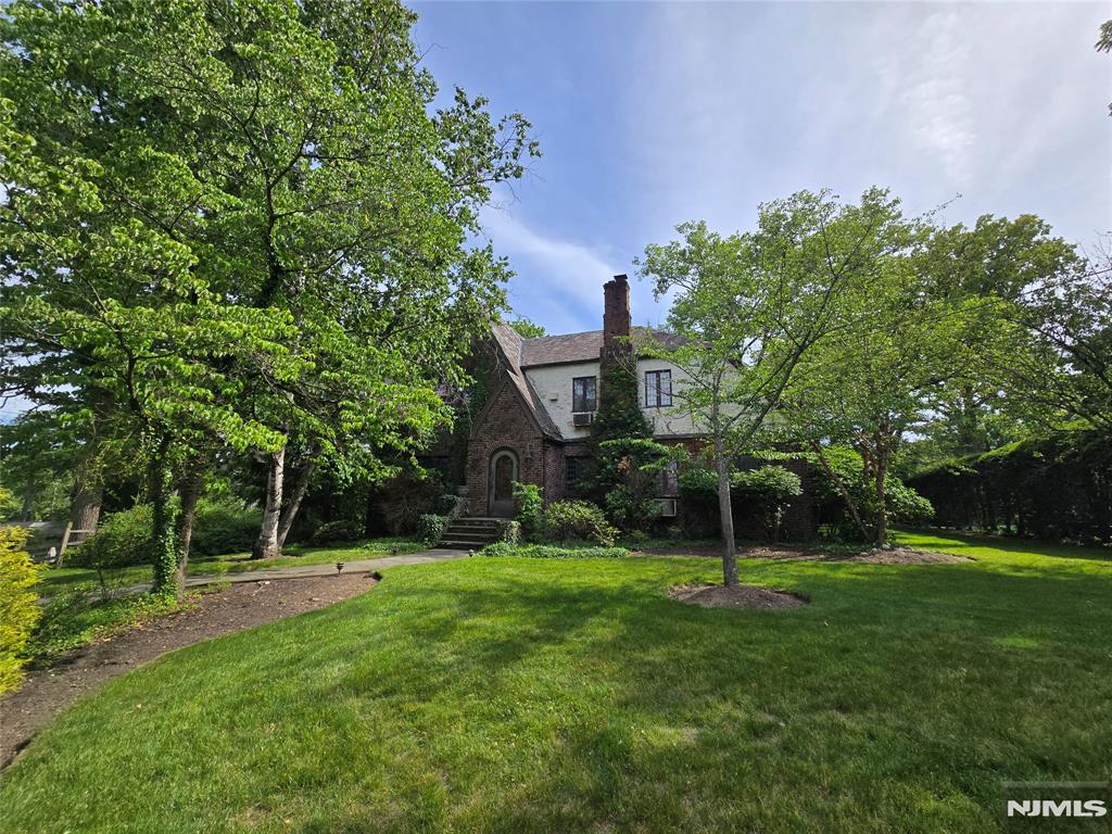 Timeless Expanded Tudor Revival residence situated on a beautifully landscaped 20,212 SF park-like property. A charming arched entryway welcomes you into this distinctive home showcasing hardwood floors, rich wood trim, and classic architectural details throughout. The gracious living room features a wood-burning fireplace, while the adjoining den offers elegant French doors and flexible living space. One of the home's most captivating features is the spacious sunroom, highlighted by exposed brick walls, a vaulted wood ceiling, and walls of windows overlooking the private backyard, creating a warm and inviting space filled with natural light. The second level features generously sized bedrooms, including a primary suite with French doors leading to a private balcony overlooking the grounds. Surrounded by mature specimen trees and lush landscaping, the expansive property offers exceptional privacy and a serene estate-like setting. Whether you choose to enjoy the home's timeless character as it is, update it to suit your personal style, or explore expansion possibilities, this unique property presents a rare opportunity. Conveniently located in one of the area's most desirable neighborhoods, this special home combines architectural charm, generous living space, and endless potential. Property is being sold strictly in as-is condition.