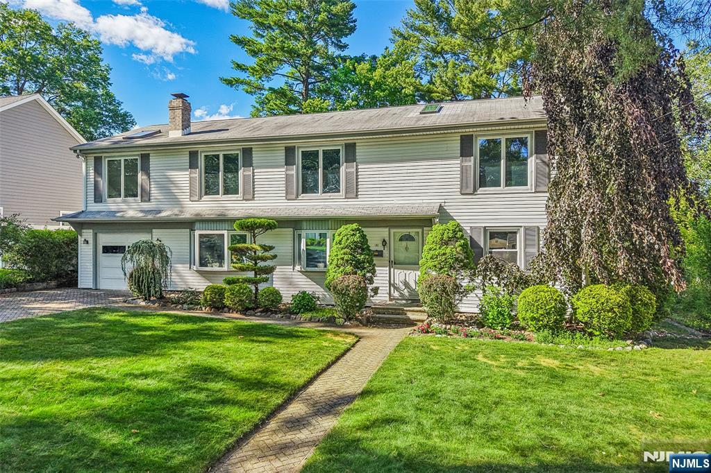 Exceptional opportunity to own a beautifully expanded Colonial in one of Paramus's most desirable neighborhoods! Situated on a quiet residential street, this home features a highly versatile floor plan perfect for large families or multi-generational living with flexible options for up to 7 bedrooms across the first and second levels. The first level welcomes you with a sunny living room that flows into an open family room and dining area centered around a warm fireplace. An eat-in kitchen, two bedrooms, a full bath, and convenient access to an extra-deep attached tandem garage complete the level. The second level boasts five additional bedrooms, two providing flexible use for an office or rec space, all with gleaming hardwood flooring throughout, alongside a second full bathroom. Set on a beautifully landscaped lot with mature landscaping and fenced yard, this home offers a mix of privacy and space for outdoor enjoyment. Additional features include a spacious second level deck, vaulted ceilings in several bedrooms, skylights, sprinkler system, central air conditioning, and a full basement with potential for future finishing. Enjoy close proximity to top-rated schools, parks, Bergen County's world-class shopping, houses of worship, and easy NYC transportation. Don't miss out on this amazing Paramus opportunity!