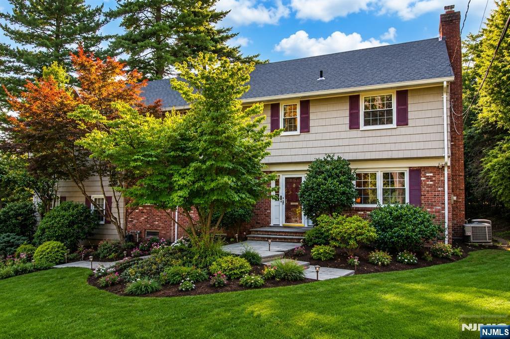 Welcome to 122 Crest Road, an elegant 5-bedroom, 3.5-bath Colonial on approximately 0.44 acres in Ridgewood's desirable Heights neighborhood. Enjoy beautiful New York City views and an exceptional location just a short walk to the Ridgewood train station, vibrant downtown, restaurants, cafes, shopping, and community events. Zoned for Ridge Elementary, George Washington Middle School, and Ridgewood High School. Inside, hardwood floors, abundant natural light, and spacious rooms create a warm, inviting atmosphere. The formal living room features a gas fireplace, while the formal dining room is ideal for entertaining. A custom Ulrich-designed kitchen offers generous cabinetry, ample workspace, and opens to the light-filled family room with dramatic vaulted ceilings overlooking the landscaped backyard. A first-floor office and laundry room add everyday convenience. The primary suite features a walk-in closet and spa-inspired bath. Four additional bedrooms and the finished basement provide flexible space for guests, recreation, fitness, or home offices. Outdoor living includes a large deck and fully fenced backyard. Additional highlights include central air, zoned natural gas heat, newer windows, a whole-house generator, an oversized 2-car garage, and a new roof and gutters (2024). Approximately 3,407 sq. ft. of thoughtfully designed living space in one of Ridgewood's most sought-after neighborhoods.
