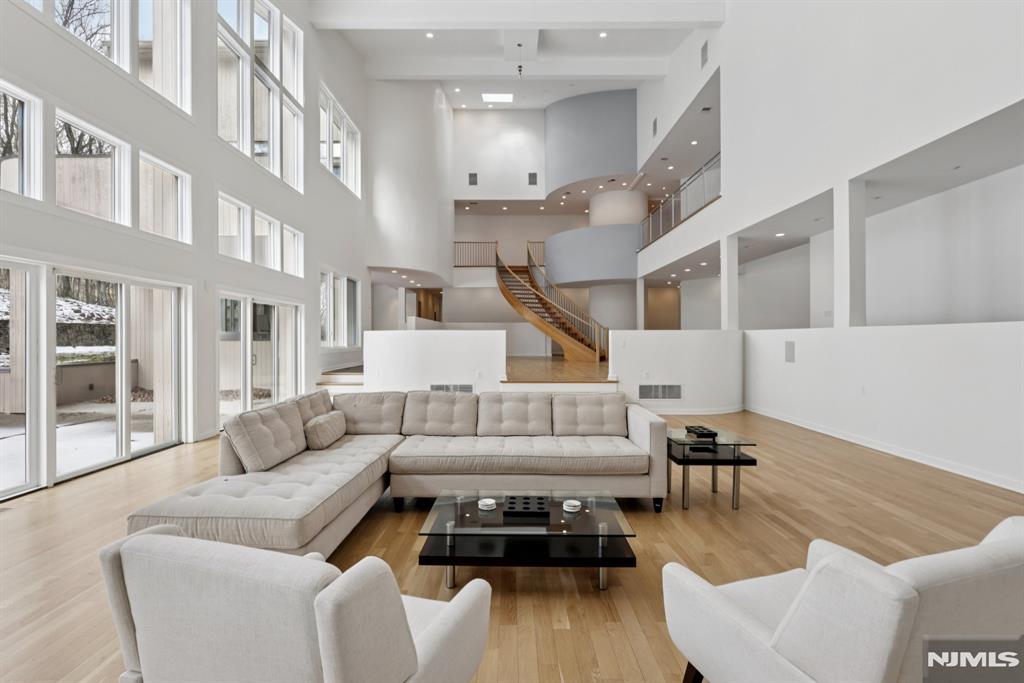 A rare architectural statement where scale, sophistication, and elevated luxury converge. Set on 3.7 private acres, the residence spans approximately 13,000 sq ft with 7 bdrms, 7 full baths and 2 half baths, designed for both grand entertaining and refined everyday living. From arrival, striking architectural lines, dramatic volume, and curated sightlines create a 'WOW' factor. The grand living room unfolds as a stunning open-concept space with soaring 32-ft ceilings, a sculptural spiral staircase, and a 2-sided 16-ft gas fireplace. Floor-to-ceiling windows flood the home with natural light, while views extend to the sun-drenched, heated indoor pool. The chef's kitchen pairs performance with modern design, featuring Wolf and Sub-Zero appliances, multiple ovens, wine refrigeration, coffee system, and premium finishes throughout. The main level also offers a private theater, gym, office, and first-floor au pair ensuite. The second level is anchored by a luxurious primary suite sanctuary with 20-ft ceilings, dual balconies, loft, sitting room, dual walk-in closets, and a spa-inspired bath with separate water closets and bidet. 4 addt'l bdrms include 3 ensuites and private balcony access.The lower level showcases the indoor pool, a 1,200-sq ft ballroom, dry sauna, full bath, and flexible space ideal for a wine room, cigar lounge, or recreation area. Additional highlights include a 4 car heated garage and dedicated elevator shaft. A truly one-of-a-kind Mendham estate!