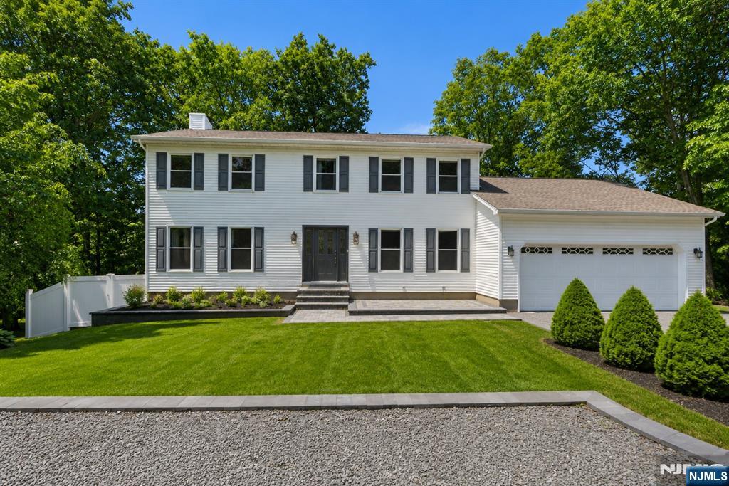 Welcome to this beautifully maintained, sun-drenched colonial home, where classic comfort perfectly balances with modern living. Located in Awosting, one of West Milfordâ€™s most sought-after neighborhoods, residents enjoy exclusive access to an array of community amenities including a private beach, a local clubhouse, and direct access to Greenwood Lake. From the moment you step through the front door into the bright foyer, you are greeted by an abundance of natural light streaming through large, elegant windows that effortlessly illuminate the spacious, open layout. The main level showcases an expansive living area with pristine hardwood flooring and crisp neutral walls, alongside a beautiful eat-in kitchen complete with warm wood cabinetry, a central island, and sliding glass doors that lead directly outside. Transition seamlessly to the massive rear deck, providing an incredible elevated space for outdoor dining, entertaining, or simply overlooking the serene, green surroundings and meticulously manicured lawn. Downstairs, a full walkout basement offers endless potential for recreation, a home gym, or additional living space with direct backyard access. Complete with a spacious two-car attached garage and exceptional curb appeal that shines both day and night, every corner of this property blends functional architectural charm with bright, airy spaces designed for modern lifestyles.