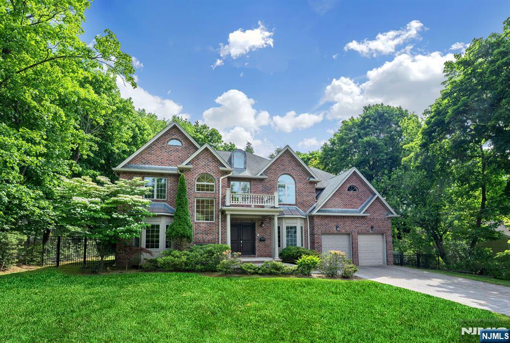 Located in Closter's sought-after East Hill neighborhood, this beautifully maintained Center Hall Colonial offers 5 bedrooms, 5 1/2 bathrooms, and an open, functional layout designed for today's lifestyle. A dramatic two-story foyer welcomes you into light-filled interiors enhanced by hardwood floors, detailed moldings, and freshly painted rooms throughout. Designed for both everyday living and entertaining, the main level features a formal living room, elegant dining room, great room with fireplace, and an eat-in kitchen with butler's pantry. A first-floor bedroom with en-suite bath provides ideal accommodations for guests, extended family, or work-from-home flexibility. Upstairs, the primary suite offers a gas fireplace, sitting room or office, dressing area, walk-in closets and a spacious bath with separate vanity areas. Additional bedrooms include a private en-suite bedroom, two bedrooms connected by a Jack-and-Jill bath, and a versatile bonus room. The finished lower level expands the living space with areas for recreation, fitness, work, creativity, and storage. Outside, a paver patio provides the perfect setting for outdoor dining and entertaining. Surrounded by mature trees and lush landscaping, the property offers exceptional privacy and peaceful views from nearly every window. Conveniently located near top-rated schools, parks, playgrounds, transportation, and Closter's vibrant downtown with its shops and restaurants.
