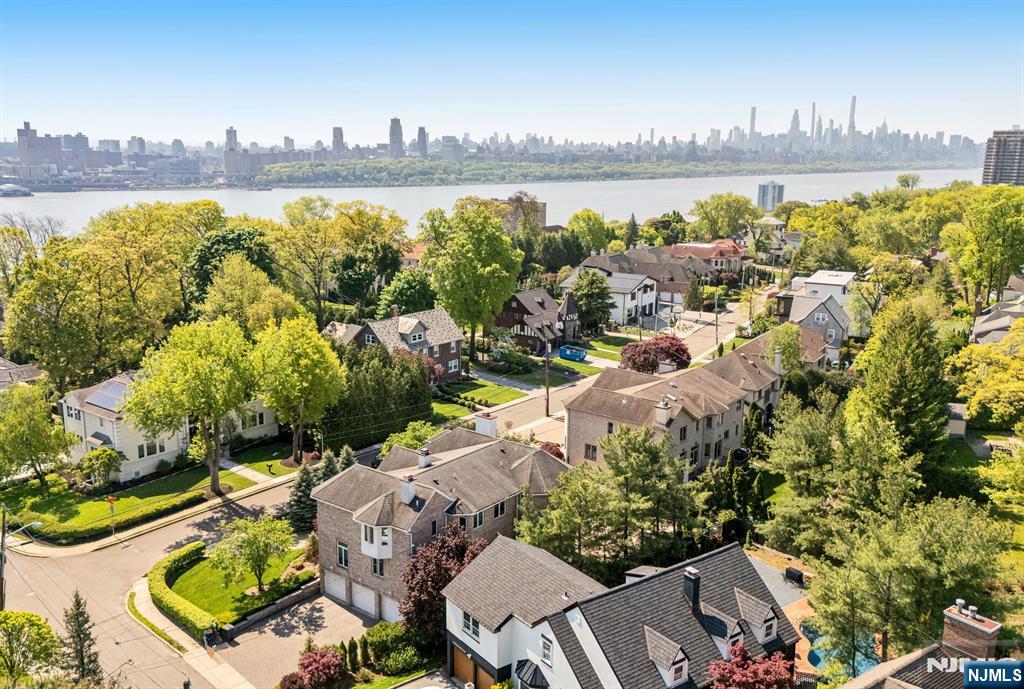 Welcome to the sought-after Bluff section of Fort Lee. East-facing Manhattan skyline views from the George Washington Bridge to Midtown. Primary suite with NYC view, fireplace, and marble spa bath. Brick Center Hall Colonial in the Bluff Section of Fort Lee. 5-bed, 4.5-bath at 1115 Arcadian Way, Fort Lee, NJ 07024. Approx. 3,904 sqft, corner lot, built 1997, renovated 2011. Primary suite: tray ceiling, picture window NYC skyline view, gas fireplace, sitting room, marble spa bath with freestanding tub, frameless rainfall shower, double vanity. Chef's kitchen: Poggenpohl Wenge cabinetry, Caesarstone counters, white quartz waterfall island, Wolf 6-burner gas range, Sub-Zero fridge, wine column, induction cooktop, slider to deck with electric awning. Two fireplaces. Two-story foyer with limestone stairs, ironwork railing, Venetian plaster. Custom Wenge doors. Central air, central vacuum.. First floor: living, dining, family room, 5th bedroom, powder room, laundry, home office. Second: primary suite with bedroom and ensuite; two bedrooms sharing a Carrara bath. Walkout ground level: rec room, den, full bath, mudroom, attached 3-car garage. Exterior: paver circular drive, raised deck, paver patio, half-court basketball, fenced yard, evergreen privacy hedges. Bluff Section of Fort Lee. Minutes to GWB ramp, NJ Transit bus to Port Authority Bus Terminal, Fort Lee Public Schools, Palisades Interstate Park, Hudson Lights, Route 4. Sitting right above the Edgewater riverfront community.