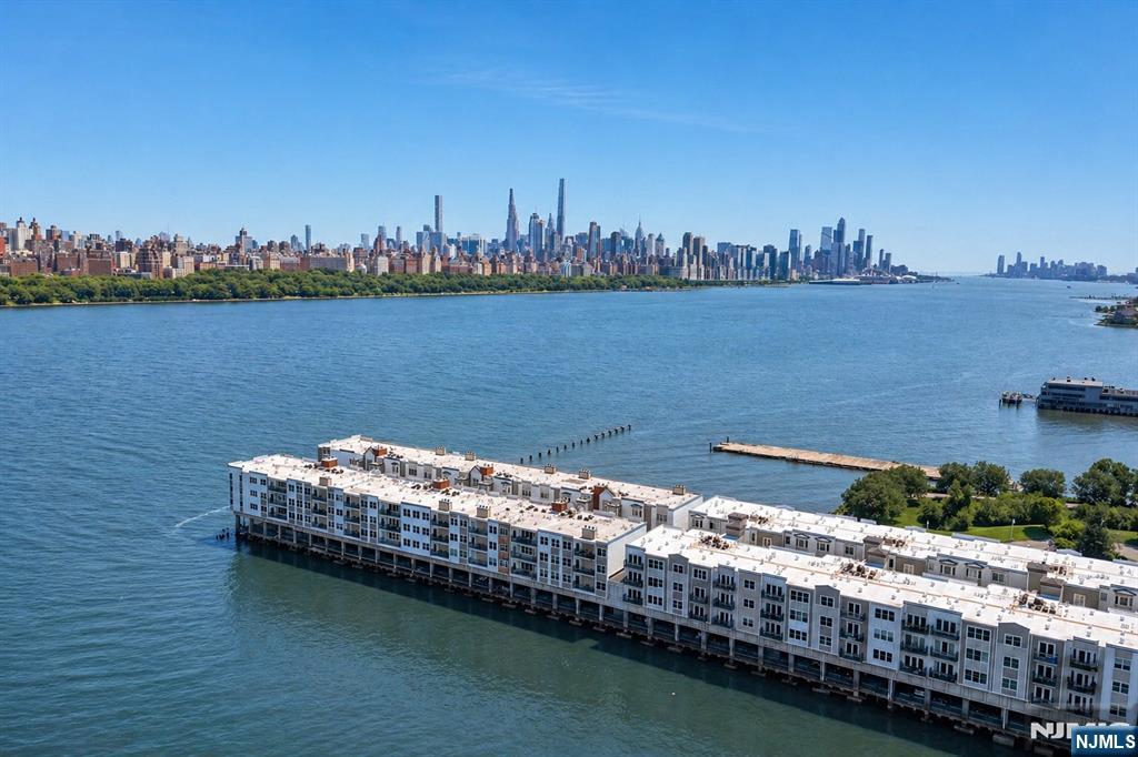 The epitome of waterfront living awaits in this stunning residence showcasing unobstructed views of the Hudson River and New York City. This exceptionally spacious 1495 SQFT two-bedroom, two-bathroom home features an open floor plan, expansive foyer, designer kitchen, beautiful hardwood floors throughout, office/den with custom French doors, and a private balcony. Thoughtful upgrades include a new hot water tank, windows, appliances, and an expanded laundry area. The Promenade is a private 24-hour guard gated community in the heart of Edgewater, offering an exceptional lifestyle, with on-site amenities including a landscaped courtyard, resident lounge, fitness center with locker rooms, showers, sauna, and whirlpool. One-car garage parking is included, while restaurants, shopping, and convenient access to NYC transportation are just moments away.