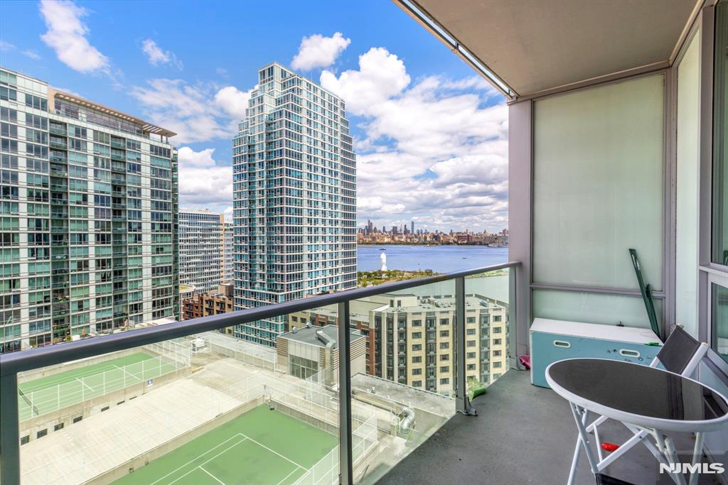 Expansive 2 bed + den corner home with private balcony and NYC views in luxury community of 20 Newport Parkway! Chef's kitchen features SS appliances, granite counter tops, and kitchen island. The primary bedroom has a walk-in closet and ensuite bathroom. Additional bedroom, bathroom, and central den space make this the perfect home. Also included are hardwood floors throughout, recessed lighting, window treatments, washer/dryer in unit, and a ton of closet space. The building's generous amenities include 24/7 Concierge, resident lounge, screening room, jacuzzi, sauna/steam room, conference room, fitness center, and a rooftop deck. Conveniently located near Hoboken & Newport PATH, Morton Williams Supermarket, and mall.