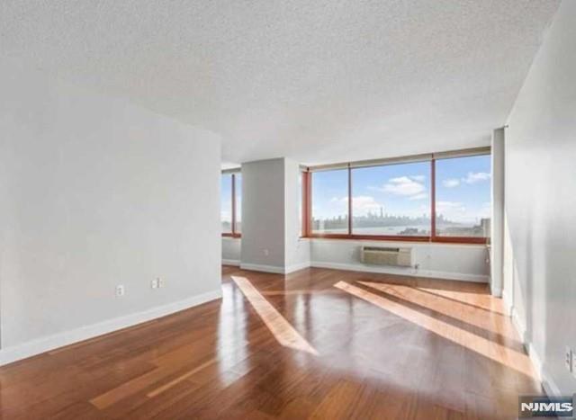 ENJOY BREATHTAKING VIEWS OF THE NYC SKYLINE AND HUDSON RIVER FROM EVERY WINDOW! This bright and spacious 1,452 sq. ft. corner unit features an inviting open floor plan with beautiful hardwood floors throughout. The property includes a recently updated heating and AC system (2023) and a newer dishwasher (2022). For ultimate convenience, an in-unit washer and dryer are also provided. Facing southeast, the home is flooded with natural light and comes with two indoor tandem parking spaces. Water is included in the rent.