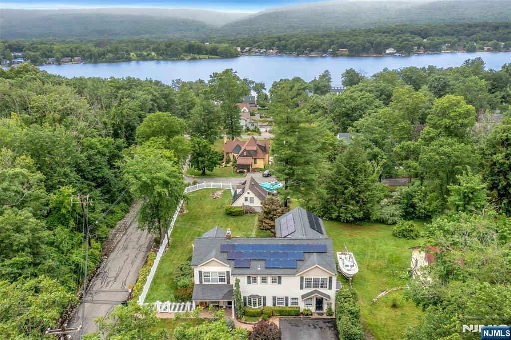 EXPERIENCE year-round LAKE LIFESTYLE with a PRIVATE DOCK ON GREENWOOD LAKEâ€™s east shore while living in this BEAUTIFUL 5 Bedroom/4.5 Bath ESTATE-LIKE HOME. Nestled in the private AWOSTING LAKE COMMUNITY, and just 15 MILES TO BERGEN CTY, this has it all! You have to love the original 1920s stone fireplace in the extended living room with bay window that captures BREATHTAKING SUNSET VIEWS. Enjoy this view from many other rooms. Designed for those who love to entertain, the home features a CHEF-GRADE GOURMET KITCHEN with an expansive island & a BANQUET DINING ROOM for holiday gatherings. The GRAND FAMILY ROOM offers ample space to gather, and the homeâ€™s true secret lies in its PRIVATE REAR EXTENDING LIVING space. This versatile wing includes a dedicated den/game room & a SECLUDED 2ND FLOOR BEDROOM/STUDIO complete with its own full bath and laundryâ€”the perfect setup for an in-law suite, home office, music/art studio, or guest retreat. The main houseâ€™s second floor hosts a LUXURIOUS PRIMARY SUITE with an ensuite bath and laundry, alongside three additional bedrooms, a hall bath, and a WALK-UP ATTIC. Perhaps the most coveted feature of all: this property conveys its own PERSONAL LAKEFRONT DOCK, your private gateway on the waters of Greenwood Lake. The rear yard is fully fenced & lawn is expansive leading to an ideal 2-car garage with 2nd floor room. This is a SMART-GREEN HOME, both Tech-Enabled & Solar-Powered! Why wait for the weekend? MAKE EVERY DAY AN ESCAPE.