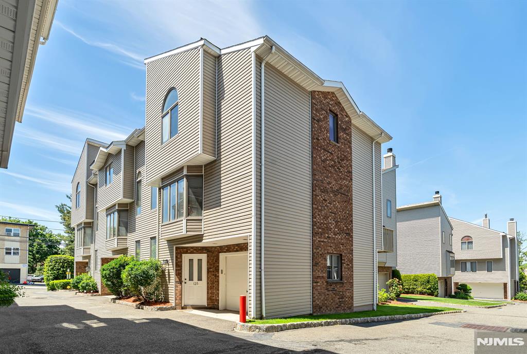 Looking for a 3-bedroom, 2.5-bathroom corner townhome with a garage in Palisades Park, NJ? This one. Three-bedroom, two-and-a-half-bathroom, 1,730-square-foot corner townhome in Palisades Park, New Jersey, Bergen County. Single-car garage with electric opener and interior access. Low HOA fee of $200 in a self-managed community with no special assessments. Ground level features a coat closet, tiled entry foyer, and a rear bedroom with two closets and its own thermostat -- usable as a bedroom, guest room, or home office. The main living level offers an L-shaped living and dining room with hardwood floors, high ceilings, a wood-burning fireplace, and an east-facing bay window. The kitchen includes a gas range, ceramic tile floors, ceramic backsplash, double sinks, stainless steel appliances, and a microwave/convection oven over the range. Full-size side-by-side washer and dryer in a dedicated laundry room. West-facing wood deck overlooks a landscaped common lawn. Central air with Nest thermostat. Gas baseboard heat. Recessed lighting. Corner unit with windows on two exposures. Primary suite features high ceilings, a large walk-in closet, and a full bath with double sinks, a standalone shower, a jacuzzi tub, a skylight, and a linen closet. Second full bath with tub and linen closet. Powder room off the living room. NJ Transit Bus Route 166 to Port Authority Bus Terminal stops on Grand Avenue. Quick access to the George Washington Bridge, Route 9W, and Route 46. Palisades Park.