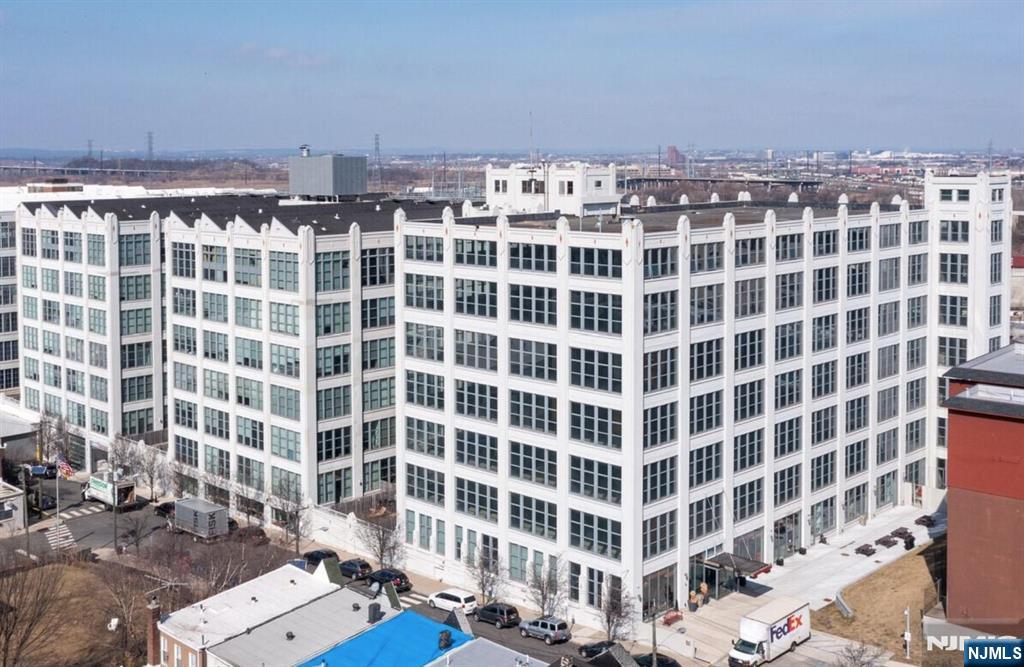 Welcome to Canco Lofts, an exquisite factory conversion in the vibrant Arts District of Journal Square, offering this modern and spacious 1-bedroom plus den (approx. 902 sq ft) that can easily function as a 2-bedroom. This stunning loft features soaring 14-ft ceilings, dramatic 11-ft picture windows with abundant natural light, wide-plank hardwood floors, and an open-concept living and dining layout. The sleek kitchen is equipped with white lacquer cabinetry, stainless steel appliances, and Caesarstone countertops, while the home is complemented by generous storage including custom California closets, oak doors, and custom blinds, along with the convenience of an in-unit washer/dryer. Residents enjoy over 10,000 sq ft of premium amenities, including a 24-hour concierge, state-of-the-art fitness center, indoor basketball court, yoga room, movie theater, resident lounge with private party space, business center, childrenâ€™s playroom, outdoor BBQ area, dog run, courtyards, and sundeck. A private shuttle to the PATH, parking available for rent, and close proximity to dining, shopping, and NYC transportation complete this exceptional offering.