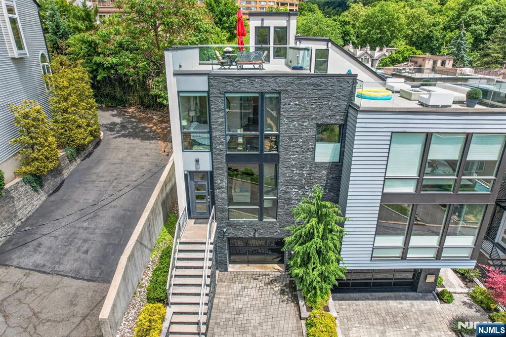 East/South-Facing Luxury Townhome with Spectacular NYC & Hudson River Views- Welcome to 14 Hooks Lane, a luxurious east/south-facing townhome built in 2018, offering approximately 3,080 sq. ft. of beautifully designed living space and breathtaking views of the Hudson River and NYC skyline. The ground level features an oversized one-car garage with a contemporary clear glass garage door, abundant storage and a secondary laundry area. The main level showcases an open-concept floor plan with floor-to-ceiling windows, a spacious living room with fireplace, dining area, powder room, and a gourmet kitchen featuring Brookhaven cabinetry, center island, and premium appliances. The second level offers two generous bedrooms, a full bath, convenient laundry area, and a stunning primary suite with a spa-inspired bath. Enjoy spectacular sunsets and panoramic city views from the rooftop terrace with frameless glass railings. Additional highlights include a private paver patio, Porcelanosa tile throughout, smart-home prewiring for cameras, speakers, and technology integration, and soaring ceilings (approximately 8' on ground level, 10' on main level, and 9' on upper level). Ideally located for an easy commute to NYC and major highways. A rare opportunity to own a modern, meticulously maintained townhome with exceptional views and luxury finishes. Truly a must-see!