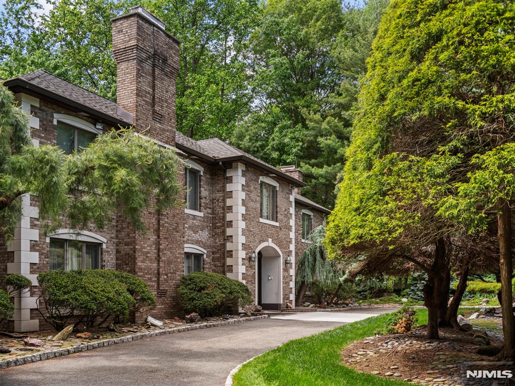 Nestled on a private 1.24-acre lot in prestigious Franklin Lakes, NJ, this masterfully custom-built 5,498 sq ft estate offers the ultimate in quiet luxury. The striking brick and stone exterior, grand circular driveway, and lush mature landscaping deliver unmatched curb appeal and total seclusion. Impeccably maintained with no expense spared, the home features a newer dual-unit heating system and multi-zone central AC. Inside, a grand foyer leads to an elegant living room, formal dining room, family room, eat-in kitchen, half bath, and a sun-drenched solarium. The second floor is a masterclass in luxury, highlighted by a massive master suite with two full baths (including a soaking tub), an attached sun room, and a private balcony. This level also features 3 additional bedrooms, 2 more full baths, a dedicated library, and an open office space. The resort-style backyard is a private oasis featuring a premium concrete and stone patio framing a sparkling gunite in-ground pool, all shielded by towering trees. This tranquil retreat is just minutes away from top-rated schools, shopping, and public transportation.