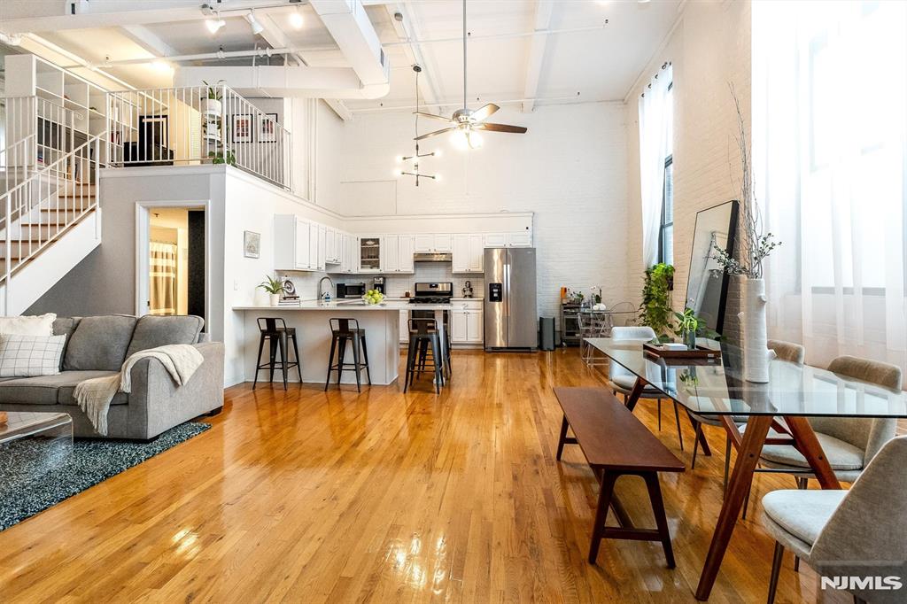 Welcome to Unit 106 at Highland Lofts, a light-filled, urban-inspired 2-bedroom loft with soaring 15ft beamed ceilings, exposed brick walls, oversized factory-style windows, hardwood floors, central air, and a modern-industrial aesthetic. Located directly across from the Highland train station, it's an NYC commuter's dream.The open-concept layout features a spacious kitchen with quartz countertops, a large center island perfect for cooking and entertaining, stainless steel appliances, and seamless flow into the expansive living and dining areas. French doors lead to the primary bedroom, complete with a generous closet and lofted space ideal for a home office, reading nook, or creative retreat. Open the doors wide and enjoy an even greater sense of openness and connection to the living space.The airy second-level loft overlooks the main living area while providing flexible space for a bedroom, office, gym, or studio. Sunlight pours throughout, highlighting the home's unique architectural details and creating a space that feels both dramatic and inviting.Additional amenities include secure intercom entry, elevator access, a private storage unit, basement laundry facilities, a pet-friendly community, and a recently renovated rooftop deck for residents and guests to enjoy. Conveniently located near public transportation (local bus right in front), the Valley Arts District, South Orange Village, Whole Foods, NJPAC, Prudential Center, restaurants, shops, and entertainment.