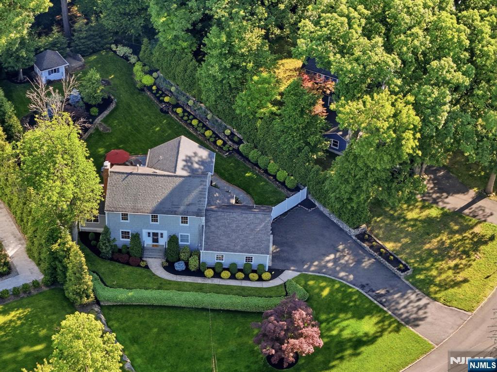 Set on nearly an acre bordering Essex Fells, this exceptional property combines extraordinary outdoor living, privacy, and a beautifully renovated Colonial with timeless charm and modern luxury. Surrounded by mature landscaping and park-like grounds, the home offers an inviting layout filled with natural light. The stunning chef's kitchen with premium appliances opens to a spacious family room with walls of windows overlooking the property. Elegant living and dining rooms are ideal for entertaining, while a cozy den with vaulted wood ceilings and exposed brick adds warmth and character. Features include hardwood floors throughout, custom millwork, updated baths, Anderson windows, recessed lighting, and abundant storage. The expanded second floor offers spacious bedrooms, including a tranquil primary suite with a walk-in closet and spa-like bath. A newly renovated hall bath with double vanity and second-floor laundry add convenience. The versatile lower level includes a full bath and flexible space for a recreation room, guest suite, gym, office, or playroom, with direct access to the attached two-car garage. Outdoor living shines with a TimberTech deck, flagstone patio, perennial gardens, all professionally landscaped. The lower portion of the property offers endless possibilities for a pool, sports court, playground. Located minutes from the downtowns of Verona and Montclair, this rare offering delivers exceptional space, privacy, and lifestyle in one remarkable setting.