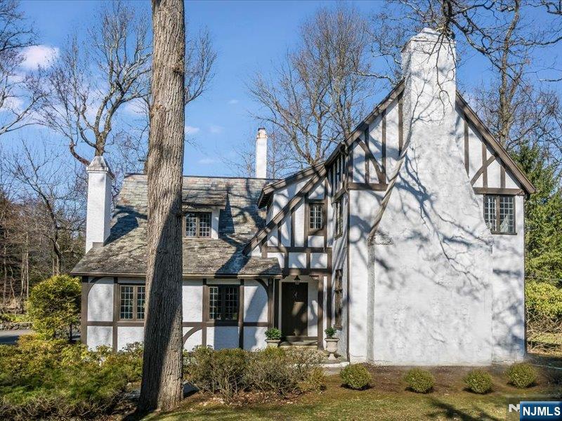 Old world craftsmanship and modern updates are a winning combination in this enchanting storybook Tudor. Rich architectural details abound - from the slate roof and half-timbered stucco exterior to leaded glass windows, linenfold doors and intricate woodwork. Inside, a gracious Living Room showcases a magnificently carved fireplace overmantel, complemented by a formal Dining Room, and an inviting Family Room with furniture quality built-ins, wet bar and gas fireplace. The updated Kitchen, equipped with high-end appliances and a center island breakfast bar opens to a sun-filled Breakfast Room. A first floor Laundry Room adds everyday convenience. Upstairs you will find four Bedrooms and two full Baths, including the serene en-suite Primary with custom closets, and a large paneled Bedroom with a cathedral ceiling. A walk-up Attic offers ample storage and the potential for future expansion. Step outside to a private bluestone Patio with hot tub, perfect for relaxing or entertaining. Located just 23 miles from NYC, Essex Fells is celebrated for its distinctive homes, top-rated schools and close-knit community. Don't miss this opportunity to own a home that blends timeless charm with modern comfort in one of northern NJ's most desirable towns.