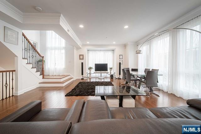 Welcome to your light-filled open concept end unit townhome in a prime location. Upon entry, you are greeted by the spacious living area with floor-to-ceiling windows. This open-concept space is rich in natural light and in-turn, very inviting. The living space is inclusive of the center-island kitchen, complete with granite countertops. Off of the kitchen is an intimate family room and balcony. The quality of construction is readily apparent in the grand ceiling height, detailed crown moldings, and gleaming hardwood flooring throughout the home. Upstairs boasts three large bedrooms including the primary suite complete with travertine tile bath with dual tub and shower. A tandem garage is attached directly to the centrally heated/cooled home. Spectacular location just off Gorge Rd - walking distance to Edgewater's riverfront and its incredible shopping and restaurants. Steps to NJ Transit and 10 minute trip to NY Waterway Ferry with midtown or downtown commuting options.