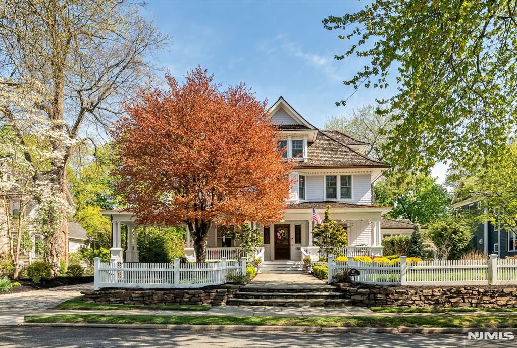 Set on a breathtaking 280-ft landscaped property along prestigious Spring Avenue, this exceptional 5-bedroom, 4.5-bath Colonial is surrounded by some of Ridgewoodâ€™s most iconic homes, offering a rare blend of timeless beauty and modern luxury. A graceful, curved white picket fence, port cochere, and cedar roof create outstanding curb appeal, while the covered front porch invites slow mornings and peaceful evenings. The backyard is a private retreat with a rear deck, greenhouse, sport court, vegetable garden, fenced lawn, and a 3-car garage with a finished loft/studio. Inside, rich original woodwork, a dramatic 3-story staircase, leaded glass French doors, stained glass windows, and coffered ceilings add warmth and character. The newly renovated custom kitchen features a 9-foot island, top-tier appliances, a cozy fireplace, and oversized sun-filled picture windows that bring the outdoors in. Formal living and dining rooms, a private office, and an updated family room with walls of windowsâ€”plus an adjoining mudroomâ€”offer both elegance and ease. Upstairs, the serene primary suite with spa-like bath is complemented by four additional bedrooms and a laundry room. The lower level adds a versatile family room, guest suite, new full bath, second laundry, hobby room, and ample storage. Ideally located near top-rated schools, downtown Ridgewood, and NYC transportation, this is a truly special home ready to be enjoyed for years to come.
