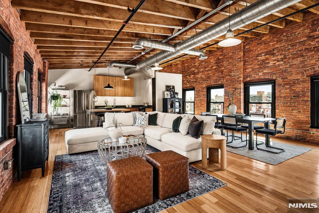 A one-of-a-kind top-floor loft at the iconic Button Factory offering soaring cathedral ceilings, dramatic open space, and the kind of authentic industrial character that is rarely available. Currently configured as a spacious one-bedroom, the layout offers exceptional flexibility to accommodate additional work or sleeping areas, or to be converted into a two-bedroom unit. Exposed brick and original beams create a warm yet architectural feel that stands apart from typical offerings. The updated kitchen flows seamlessly into generous living and dining areas ideal for entertaining or simply enjoying the space. Multiple exposures flood the unit with natural light and give the option for cross ventilation, while direct access to an outdoor space adds a rare and highly desirable extension of the home. Additional highlights include in-unit laundry, ample storage with two dedicated private storage areas, and a beautifully designed courtyard with convenient elevator access. Ideally located just one block from Newark Penn Station for an easy and fast train commute to Manhattan (20-minute train ride to World Trade Center or Penn Station NYC);10 minutes by car to Newark Liberty International Airport. Enjoy close proximity to premier entertainment venues such as the Prudential Center, New Jersey Performing Arts Center, and the Ironbound's vibrant restaurant scene. Walk Score of 90; Transit Score of 96. Gated parking available for an additional monthly fee.
