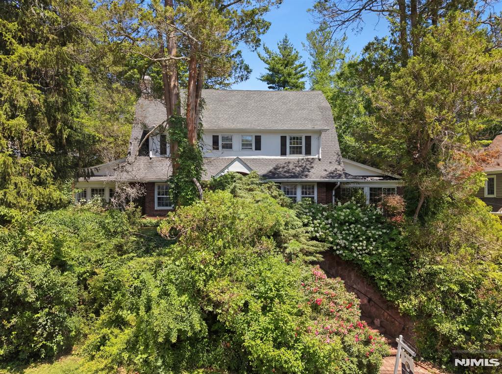Tucked behind lush, blooming landscaping is this elegant Colonial, on one of Tenaflyâ€™s most sought-after streets. This home offers timeless charm, generous living spaces, beautifully appointed wood doors & floors & a serene connection to nature. Step into a welcoming foyer with a beautiful sightline through to the breathtaking backyard. A spacious formal dining room flows effortlessly into a sun-drenched family room featuring floor-to-ceiling windows and sliding doors that open to the tranquil outdoor retreat. The kitchen is designed for both everyday living & entertaining, with a breakfast bar, two sinks, & abundant counter space. A grand formal living room with fireplace provides an elegant gathering space, complemented by an additional light-filled room perfect for a home office, library, or sitting room. The second level offers three generously sized bedrooms, including a luxurious primary suite with private bath, & spacious hall bathroom. The third floor provides a flexible space with an additional bedroom, a bonus room perfect for an extra bedroom/office & full bath. Finished lower level includes a powder room, large rec room & direct access to the two-car garage. Step outside & discover a peaceful, private retreat perfect for relaxation. This stunning & sophisticated home combines elegance, comfort, & location, with access to award-winning Blue Ribbon schools. A rare opportunity to experience refined living in one of Tenaflyâ€™s premier neighborhoods.