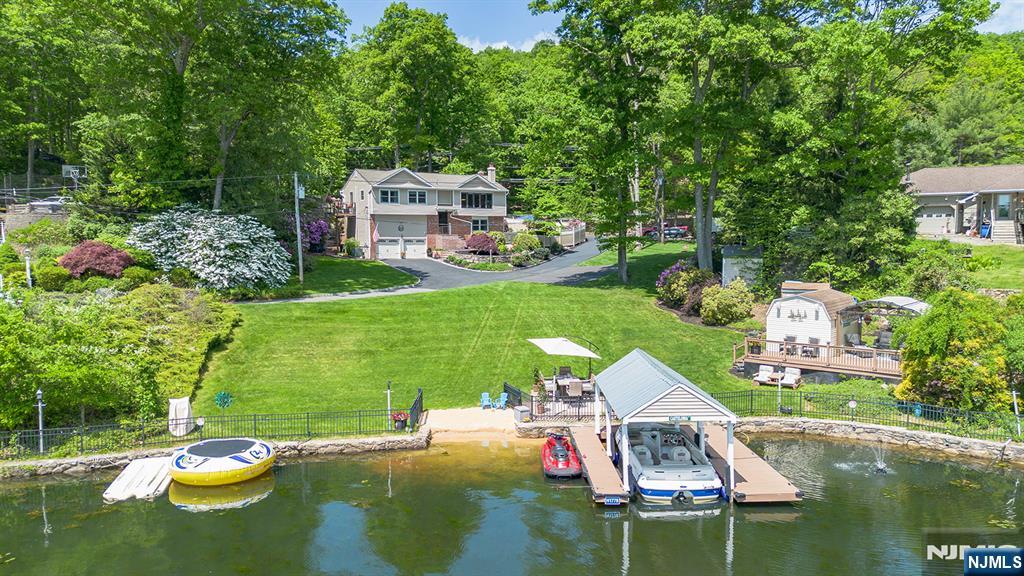 Welcome to your private Lake Hopatcong retreat! Set on 1.2 beautifully landscaped acres with an incredible 135 feet of lake frontage including a covered boat dock, this exceptional home offers the perfect blend of privacy, nature, and lakefront living. The quiet cove location keeps waves and noise at bay while the small sand beach area adds fun for all. The lake front space offers a perfect gathering space for entertaining with a lawn, deck and patio for wonderful summer days and nights. The back feels like you've entered a retreat center with beautiful walking paths, peaceful waterfalls and pond. The additional decking and patio makes for multiple gathering places designed to please. Inside, the home offers a warm and inviting layout with large windows that capture breathtaking lake views while spacious gathering areas flow seamlessly to the outdoors. Many recent updates including 2 baths, roof, siding, gutter, chimney liners and more. This park-like property creates a resort-style setting rarely found on Lake Hopatcong, with mature landscaping, natural stone accents, and multiple areas to relax and enjoy the beauty of nature and the lake. Whether you're looking for a year round residence, the ultimate weekend getaway or a place to rent to others, this one of a kind property offers an extraordinary lifestyle experience on New Jersey's largest lake.