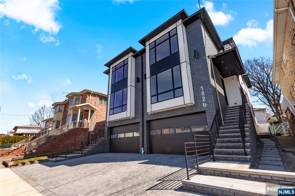 A modern home with hardwood flooring throughout and high ceilings. The living room features a sleek linear fireplace, creating a stylish and cozy ambiance. The large chef's kitchen is designed with floating countertops, a large kitchen sink, and a paneled refrigerator/freezer, with a wine cooler and a large kitchen island, providing plenty of space for cooking and entertaining. The top floor of the house includes three large bedrooms and two full baths, with the master bedroom featuring a spa-like master bath with heated floors, a large freestanding tub, glass rainfall shower, and dual vanities. The house is equipped with high-efficiency AC and hydronic heating systems, as well as central vacuuming. It is also smart home-enabled with an ultra-quiet WIFI garage door opener and built-in security cameras, providing convenience and security for the homeowners.