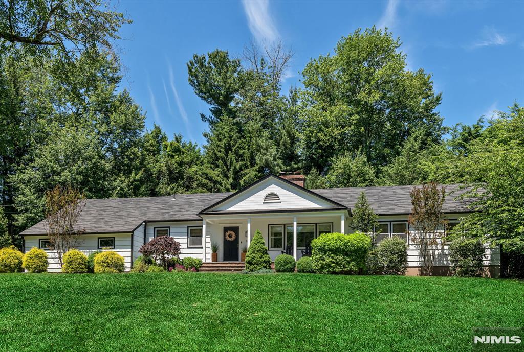 This Inviting center hall ranch, with 3 bedrooms 2.5 baths, is elevated & set back on over a half acre on one of Wyckoff's most coveted streets. Expansive front lawn, mature tree-framed grounds & fully fenced yard. Rare on-grade 2-car garage on an elevated lot. Sun-drenched living room with wood-burning fireplace to one side, dining room with custom wallpaper, classic moldings & designer lighting to the other. Gut-renovated less than a year ago, fully custom open-concept kitchen and family room is the heart of the home. Oak cabinetry, full-slab Taj Mahal Quartz counters & backsplash, Cafe#233; Series appliances with brass hardware, pocket appliance hutch, pop-out outlets & workstation sink. Warm wood & brass as one considered palette. Open concept flows into the family room: gas fpl, custom built-ins & recessed lighting. Wide-plank LVP flooring throughout. The half bath continues the oak, stone & brass finishes. Main-floor laundry with upgraded washer, dryer & custom storage. Primary suite with walk-in closet & updated en suite bath, plus two additional bedrooms. Step downstairs and the home doubles. Spanning the length of the home: flex space, custom storage & carpeted athletic area. Designer lighting, custom wallpaper in select rooms, crown moldings & custom shades layer warmth throughout. Central A/C, 3-zone heat, whole-house generator, water filtration, alarm & hot tub pre-wire. NYC bus steps away.