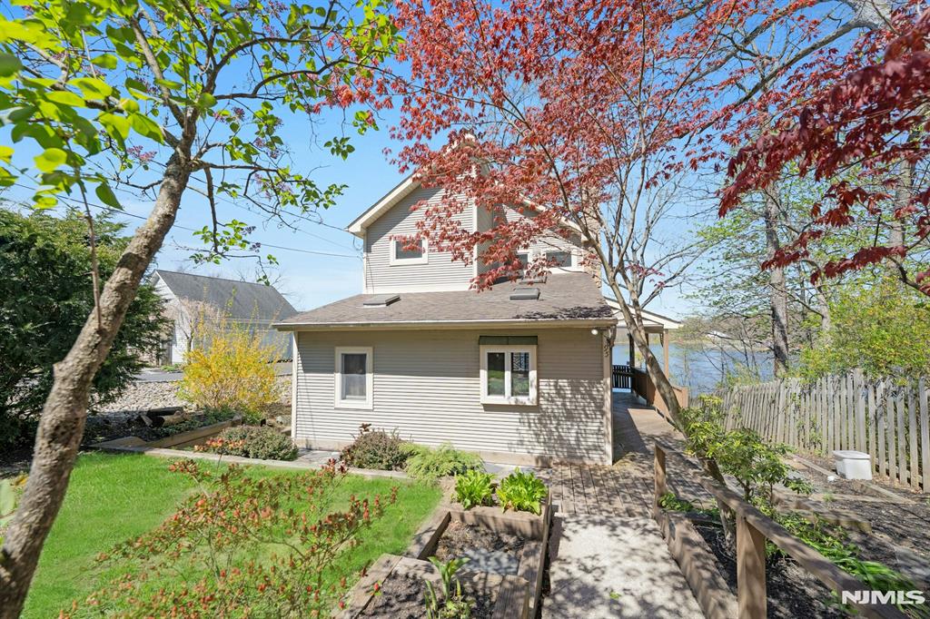 Escape to this charming lakefront chalet offering 2 bedrooms and 2 full baths, perfectly designed to create enduring memories, capture breathtaking water views and unforgettable sunsets. The main living area features a warm and inviting dining and living room that opens to a lakefront deck, ideal for relaxing, entertaining or dining al fresco. The beautifully updated kitchen, with a unique stained glass detail over the breakfast bar, is a standout, complete with granite countertops, stainless steel appliances, recessed lighting, and a skylight that fills the space with natural light. Upstairs, the primary bedroom is a true retreat with its own skylight, walk-in closet, and private lakefront balcony perfect for quiet mornings overlooking the water. Solid wood doors throughout are quality & add character.The full walkout basement houses the laundry room and provides additional flexible space with direct access to the outdoors. Outside enjoy the wraparound deck on the main level, or head down to the newer dock, which includes a canoe for immediate lake enjoyment. Additional highlights include a huge 2-car garage with an expansive loft area ideal for storage, a studio, or workshop and a generator for added peace of mind. The location is convenient to several major highways and is approximately 1 hour commute to Manhattan by car. Optional HOA dues; buyer to verify. This is lakefront living at its finest, blending charm, comfort, and lifestyle.