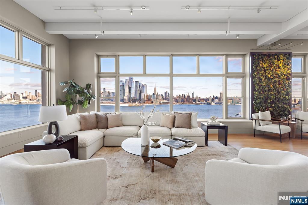 Perched above the Hudson River in the iconic Hudson Tea Building, this extraordinary corner loft offers a rare combination of authentic loft scale, refined modern design, and commanding, unobstructed views of the Manhattan skyline. One of the few true waterfront loft residences in Hoboken, Residence 11FG captures sweeping panoramas stretching from the George Washington Bridge to the tip of Manhattan, with iconic landmarks including the Empire State Building and One World Trade Center framed by oversized 10-foot windows throughout. Originally a historic tea factory, the home has been masterfully transformed through the seamless combination of two residences into an approximately 3,000 square-foot 4BD 4.5BA architectural showpiece. Conceived by the acclaimed design team of Marchetto Higgins Stieve (architecture), Virserius Studio (interiors), and Lumen Architecture (lighting), the residence balances industrial loft character with sophisticated contemporary design.
