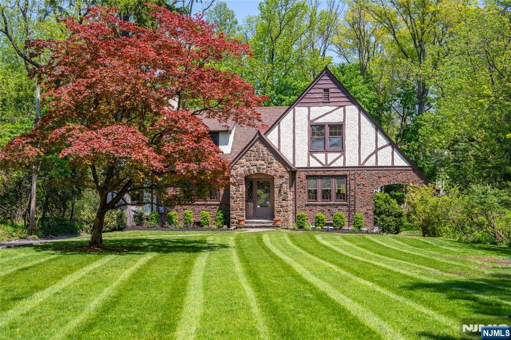 Don't miss this rare opportunity--first time on the market in over 30 years. This timeless Tudor blends classic elegance with modern luxury and is set on a stunning 0.52-acre lot with a large yard and lovely landscaping. Set back approximately 150 feet from the road, the home offers added privacy, helps minimize road noise, and maintains exceptional curb appeal. Inside, classic Tudor charm meets thoughtful modern updates. A spacious foyer welcomes you into bright, refined living spaces with tasteful finishes and a seamless flow. The living room opens to a sun-filled family room with lovely wooded views and access to a large deck, perfect for relaxing or entertaining. A flexible room can serve as a bedroom, office, or guest room. The formal dining room leads to a stylish custom kitchen with a built-in laundry closet. A powder room tucked behind the stairs adds convenience to the main level.Upstairs, the primary bedroom offers ample closet space, a sitting area, front and backyard views, and a private en-suite bathroom. Two additional generously sized bedrooms share a full bathroom. The basement provides extra space for storage, a home gym, or recreation. A large two-car garage connects to the backyard, with additional parking for multiple cars.Ideally located just minutes from Short Hills and Millburn train stations, highly rated assigned public schools, and renowned private schools including The Pingry School and Far Brook School.