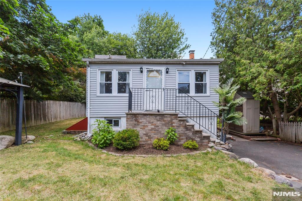 Tucked away on a private, tree-lined lot, this charming ranch offers the perfect blend of cozy character, flexible living space, and outdoor enjoyment. This 2-bedroom, 1-bath residence features an inviting open-concept layout with abundant natural light, hardwood-style flooring, and a spacious living and dining area centered around a classic brick fireplace. The functional kitchen offers ample cabinet and counter space and provides easy access to the backyard, making everyday living and entertaining a breeze. The finished lower level adds valuable flex space ideal for a family room, home office, gym, or recreation area, along with a dedicated laundry area and additional storage. Outside, enjoy a large deck overlooking the fenced backyard surrounded by mature trees, creating a private setting for relaxing, gardening, or hosting gatherings. A storage shed and off-street parking add to the home's practicality. Situated near local lakes, parks, hiking trails, shopping, dining, and major commuter routes. Conveniently located with easy access to Route 23 and nearby amenities while still enjoying the peaceful surroundings that make West Milford so desirable.