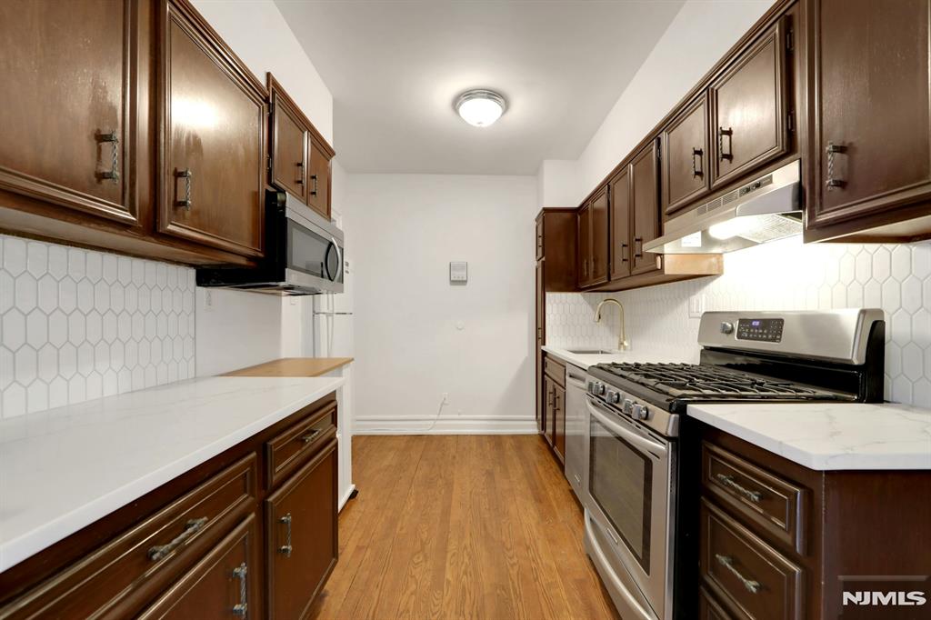 Located in Dwight Manor, this second-floor condo offers a bright layout with hardwood floors, updated finishes, and close proximity to local amenities. The spacious living room includes a wood-burning fireplace and large windows that provide natural light. An updated kitchen features stainless steel appliances, tile backsplash, and white countertops. Both bedrooms offer generous space and double windows. The full bathroom includes a tub/shower and classic tile. Additional features include radiator heat, window A/C units, tall ceilings, and an efficient floor plan with a defined dining area. On-site laundry, assigned outdoor parking, and elevator access add everyday convenience. HOA includes water, heat, hot water, common area maintenance, and trash removal. Approximately 0.1 mi to the NYC bus, 0.2 mi to Englewoodâ€™s shopping and dining district, 0.3 mi to grocery options, and 0.4 mi to nearby parks. Located near the center of town with access to major roadways and local services.