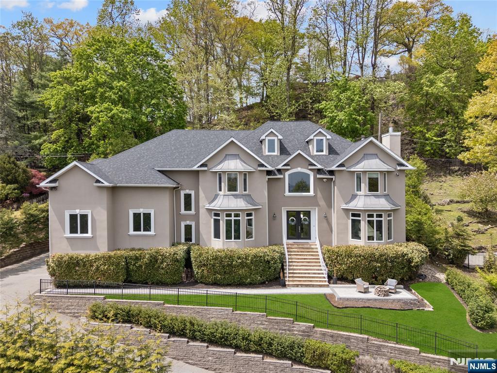 An exceptional custom residence designed for designed for those who value space, scale, and elevated living, this home offers expansive living across every level complemented by sweeping NYC skyline views that create a truly unforgettable backdrop. Thoughtfully designed for both grand entertaining and everyday comfort, the home features elegant formal spaces alongside a generous Family Room, creating the perfect balance of sophistication and livability. At the heart of the home, a chef's kitchen impresses with a large center island, premium finishes, and a sun-filled dining area ideal for gathering, hosting, and daily living. The lifestyle continues on the first floor with a dedicated Game Room and a large Guest Suite/Office. The fully finished lower level with a Gym and play space, offers exceptional flexibility for recreation, media, or fitness. Private spaces are equally refined, with beautifully updated baths. The Primary Suite is large with walk in closets, a deck over looking landscaped and wooded grounds, and a Primary bath that evokes that a spa-like experience, combining modern design with timeless luxury. Four additional bedrooms and 3 baths complete the second floor. Whether hosting on a grand scale or enjoying quiet moments with the city skyline in view, this home delivers the space, comfort, and setting today's luxury buyers are seeking.