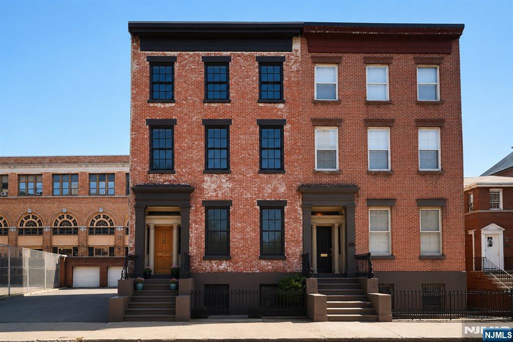 This exceptional 25-foot-wide single-family brownstone is located in the highly sought-after Paulus Hook neighborhood of Jersey City. Offering approximately 3,800 square feet, this home features up to 5 bedrooms and 3.5 bathrooms, seamlessly blending historic charm with modern luxury. The chef's kitchen showcases Calacatta marble countertops, a large island, custom solid wood cabinetry, Wolf 6-burner gas range, Bosch refrigerator and dishwasher, Bertazzoni double wall oven, built-in pantry, and a bar with a Marvel wine refrigerator. Radiant heated bluestone floors lead to French doors opening onto a private bluestone patio with a gas-connected grill and professionally landscaped garden. The elegant parlor level features original pocket doors, walnut built-ins, plaster moldings, inlaid oak floors, Roll & Hill chandeliers, and two original ebony marble mantels. Upper levels offer flexible living with spacious bedrooms, a marble bath with Kohler fixtures, and a top floor that can serve as a luxurious primary suite or oversized children's suite with additional rooms for offices, guests, or an au pair. Additional highlights include multi-zone central air, three skylights, Nest thermostats, keyless entry, Electrolux laundry, and rented garage parking. Just minutes from Grove Street and Exchange Place PATH, NYC ferries, Liberty State Park, PS16, Whole Foods, and the future Trader Joe's and Equinox, this home offers the perfect blend of luxury, convenience, and timeless character.