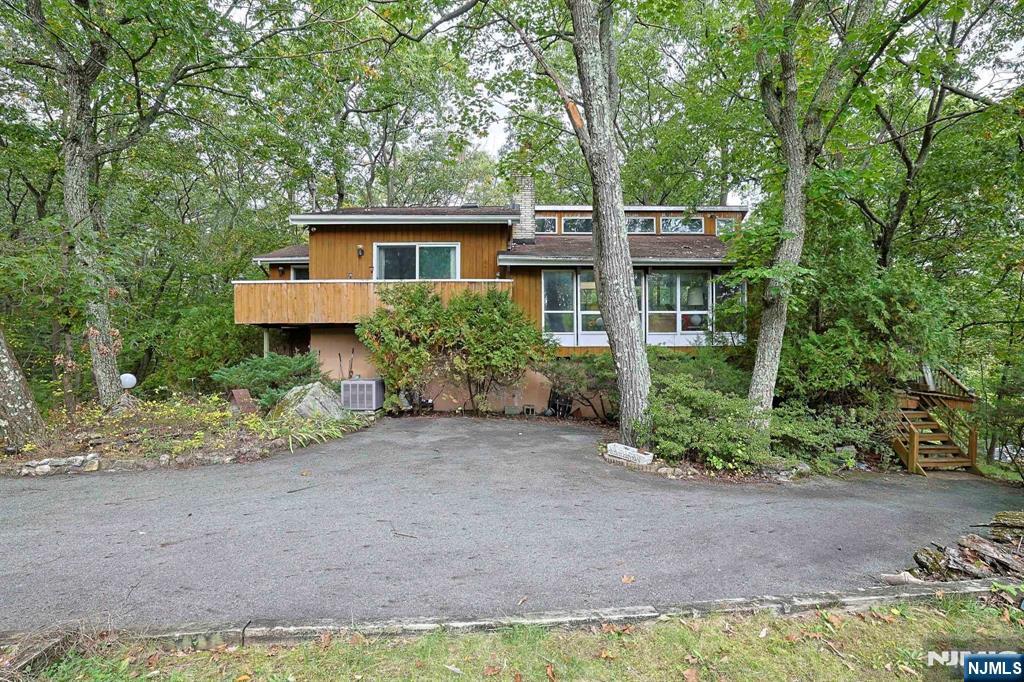 An incredible opportunity in a desirable section of Ringwood. A 3 bedroom, 2 &1/2 bath custom contemporary home with a BRAND NEW 3 BEDROOM SEPTIC, also boasting a renovated kitchen that features two ovens. The living room is adorned with a wood burning fireplace and large windows which offer mountain views and flood the living area with natural light. The ground floor's family/rec room is outfitted with another wood burning fireplace and a full bath with a Jacuzzi bathtub. There is ample storage throughout the ground floor. Multiple sliding doors throughout the home offer access to rap-around decks. Large driveway with plenty of parking. A backyard with two storage sheds. The kitchen is the most recent update to the home, yet the rest of the home is in need of a remodel, A new owner occupant can build instant equity with the right upgrades to this unique home. Investors are also welcome! Home is being sold strictly AS IS with no know issues to the major mechanical systems. Close to bus stops and access to rt 287.