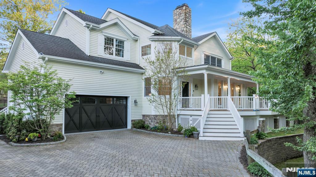 Tucked at the end of a quiet cul-de-sac in Demarest and surrounded by protected natural landscape, this home unfolds with cinematic beauty in every season. A pond with flowing fountain, wraparound Ipe lemonade porch, and walls of windows overlooking nature create a constant connection to the outdoors across 2.65 private acres. Inside, freshly refinished light wood floors, newly painted interiors, and a soaring two-story foyer filled with sunlight set the tone. The open layout flows naturally from the family room with fireplace into the renovated chefs kitchen and breakfast area, while a dramatic mahogany-clad lounge with towering fireplace feels transported from a private luxury hotel. Multiple work-from-home spaces, including a private-entry office, offer exceptional flexibility. Upstairs, all four bedrooms are en suite, including a striking primary suite with cathedral ceiling, fireplace, custom walk-in closet, and newly renovated spa bath featuring radiant heated floors, steam shower, soaking tub framed by a picture window, and linear fireplace. The walk-out lower level offers expansive recreation space, natural light, a legal bedroom suite, and flexibility for guests, fitness, or extended stays. Extensive updates throughout, 6-zone HVAC, generator, EV charging, top-rated schools, and easy access to NJ Transit and the George Washington Bridge complete the home.