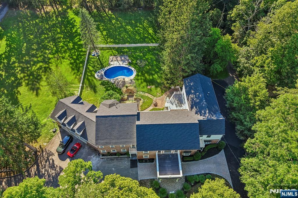 Set on 2.86 private acres, 1050 Ramapo Valley Road is a rare Mahwah estate that delivers the scale, privacy and finish level buyers usually associate with Franklin Lakes or Saddle River. Virtually every space has been reimagined with top-of-the-line materials, natural stone, oversized doors, custom millwork and a crisp, sophisticated design throughout. Offering approx. 8,256 sq ft above grade plus an estimated 2,800 sq ft finished lower level, the home provides exceptional room for everyday living, entertaining, guests, work, fitness and multigenerational flexibility. The dramatic main level centers around expansive living and dining areas and a stunning Dacor-appointed kitchen with generous prep, storage and gathering space. A remarkable 2,000+ sq ft primary wing feels like a private retreat, with a sitting room, spa-style bath and exceptional dressing/closet space. Multiple ensuite bedrooms, flexible offices, lounge areas, laundry on the bedroom level, a finished lower level with bar and entertainment room, and a 5-car garage create a home that is both practical and extraordinary. Outside, the acreage provides privacy, presence and breathing room rarely found at this level. From the scale of the rooms to the quality of the finishes, this is the kind of property that cannot be fully appreciated on paper. It needs to be walked, felt and experienced in person. A fully elevated estate with uncommon acreage, volume and sophistication.