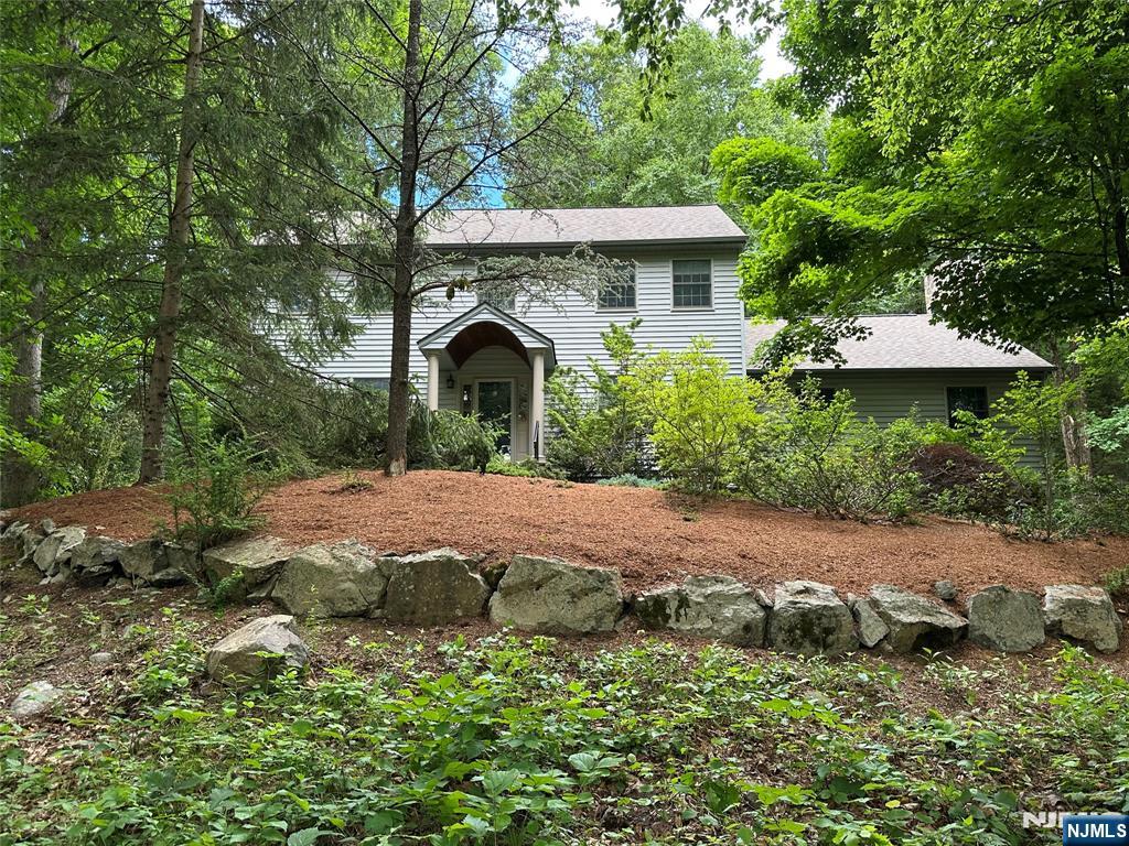 Escape the hustle and bustle to your own private mountain oasis! Nestled at the end of a quiet cul-de-sac on 1/53 pristine, wooded acres, this spectacular 4-bedroom, 2.5 bathroom custom colonial backs directly to a 500+ acre protected preservation tract. Set back on a scenic prominence, this home offers a rare level of seclusion where every window frames stunning views of the lush tree canopy, giving the peaceful feel of a virtual tree treehouse. Step inside to an expansive, sun-drenched great room featuring dramatic vaulted ceilings, striking log walls, and a majestic floor-to-ceiling stone fireplace. The layout flows seamlessly into a tastefully appointed chef's kitchen, complete with high-end appliances, granite countertops, a separate breakfast nook, and a spacious pantry. Upstairs, you will find four spacious light-filled bedrooms designed for rest and relaxation. The outdoor living spaces truly set this premium property apart. Enjoy your morning coffee on the expansive deck, or unwind in the private, natural log-constructed lanai. Located at the very edge of a desirable lake community, you get ultimate privacy along side an effortless commute. Situated near Routes 23 and 287, you are just 2 miles from the NYC Metro park-and-ride lot and minutes from Crystal Springs Golf & Country Club, wineries, skiing, and hiking. This turn-key property is completely move-in ready with all inspections completed for a quick, hassle-free close!