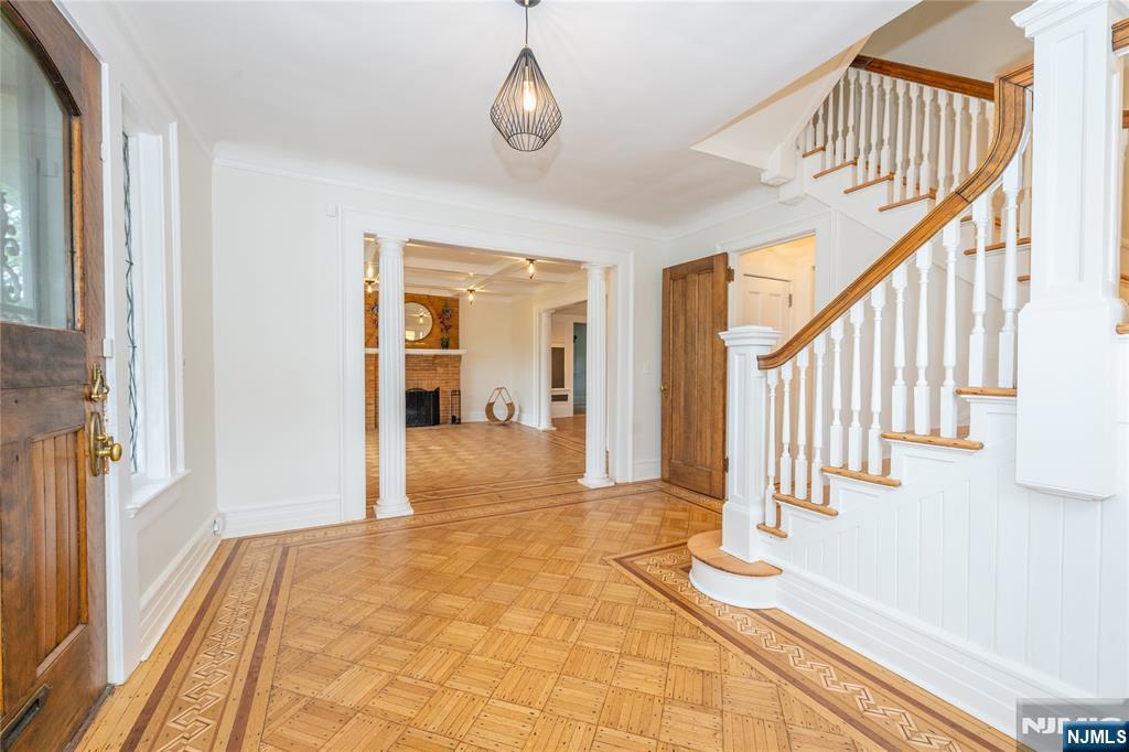 Set on one of Montclair's most exclusive and sought-after streets, this five-bedroom, three-bath residence is a masterful expression of architectural heritage, timeless craftsmanship, and refined living. Ideally positioned just moments from Montclair's vibrant downtown, acclaimed restaurants, cultural attractions, and direct NYC transportation. A stunning entry foyer introduces interiors of remarkable scale and elegance. Rich in character and architectural significance, the home showcases beautifully preserved original woodwork, jewel-toned stained glass, grand coffered ceilings, and exquisite parquet hardwood flooring with decorative border inlays, creating an atmosphere of timeless sophistication. Throughout, museum-quality millwork, artisan-crafted detailing, and heirloom-quality finishes celebrate the home's enduring craftsmanship and historic integrity. The formal living and dining rooms are distinguished by their impressive proportions, abundant natural light, and architecturally significant details. A versatile first-floor room offers exceptional flexibility and may serve as a family room, guest suite, private office, or first-floor bedroom. The upper levels continue the home's legacy of elegance. The expansive primary suite is a true retreat, featuring generous dimensions, a charming fireplace, and serene views. Two additional bedrooms on this level. Occupying the third floor, a remarkable secondary primary suite includes a walk-in closet and full bath.